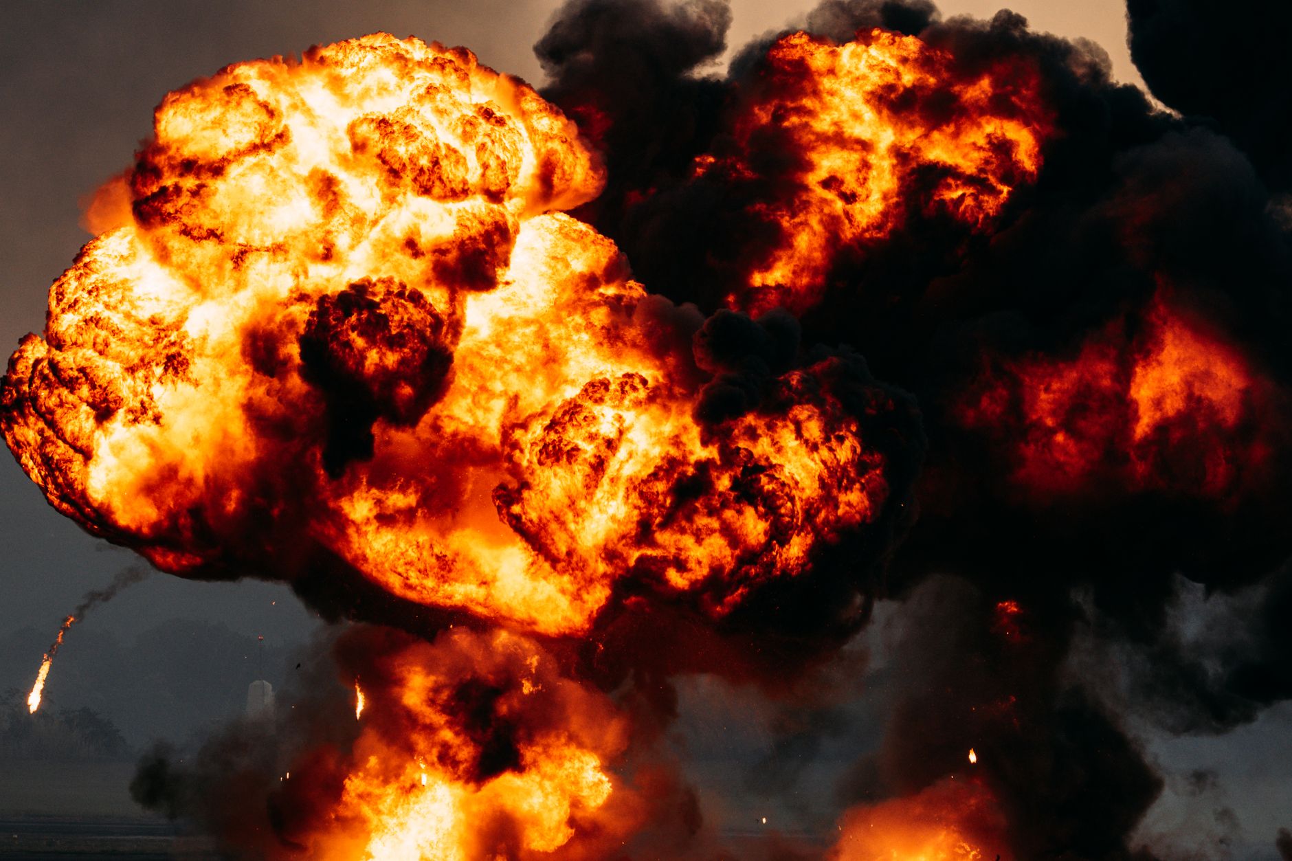 Intense explosion with fiery flames and dark smoke billowing skyward, showcasing dramatic impact.
