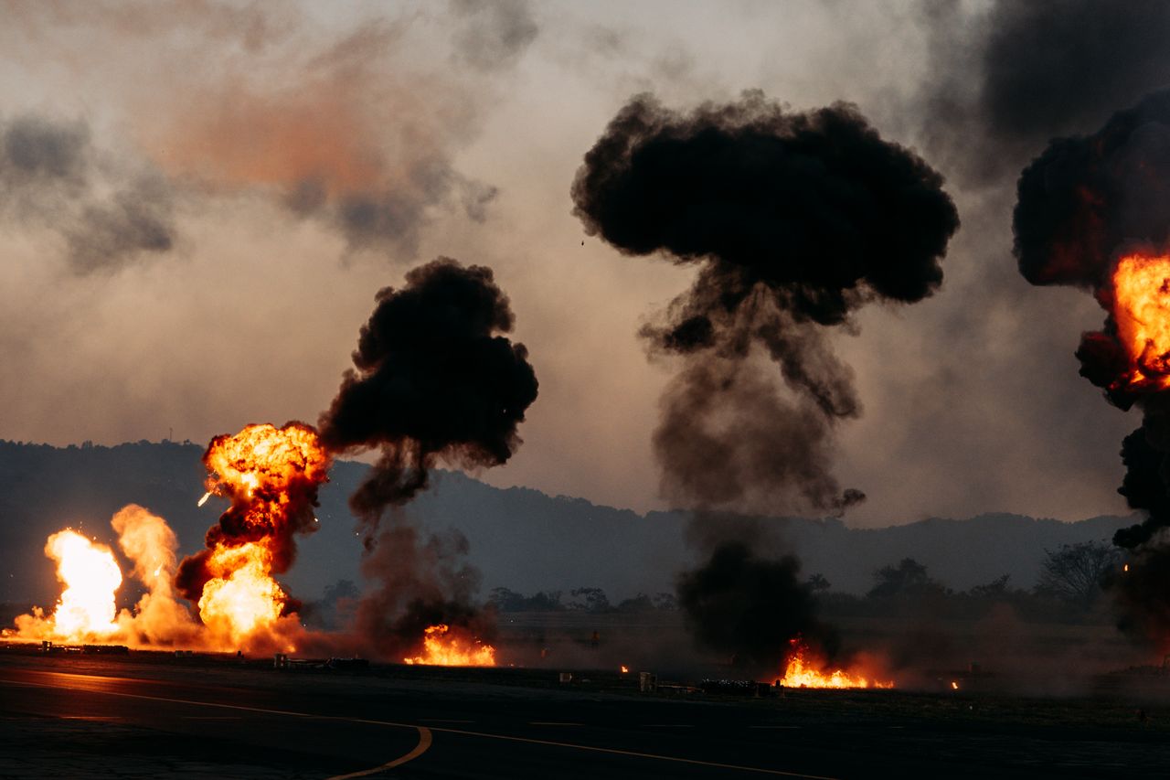 dramatic scene with explosions and thick black smoke rising in an outd