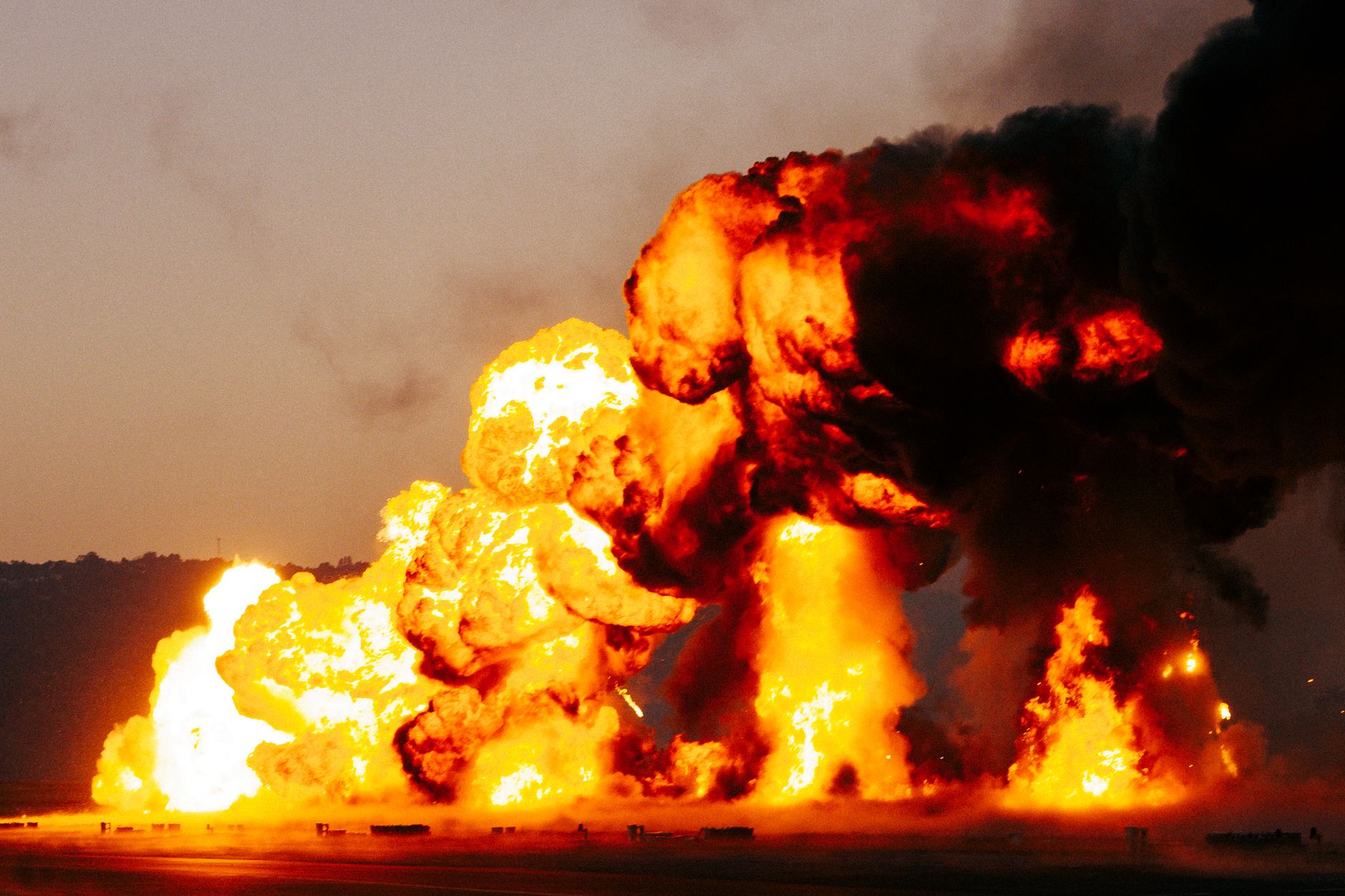 A powerful explosion with intense flames and dark smoke creating a dramatic outdoor scene during daytime.