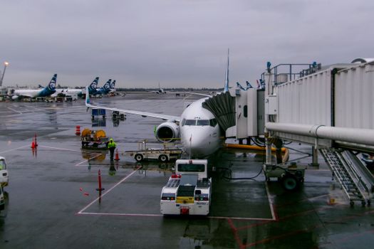 A passenger airplane docked at SeaTac Airport during a rainy day, showcasing airport operations.