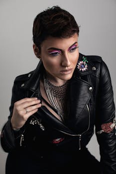 Elegant studio portrait of a female model with vibrant eye makeup and a black leather jacket.