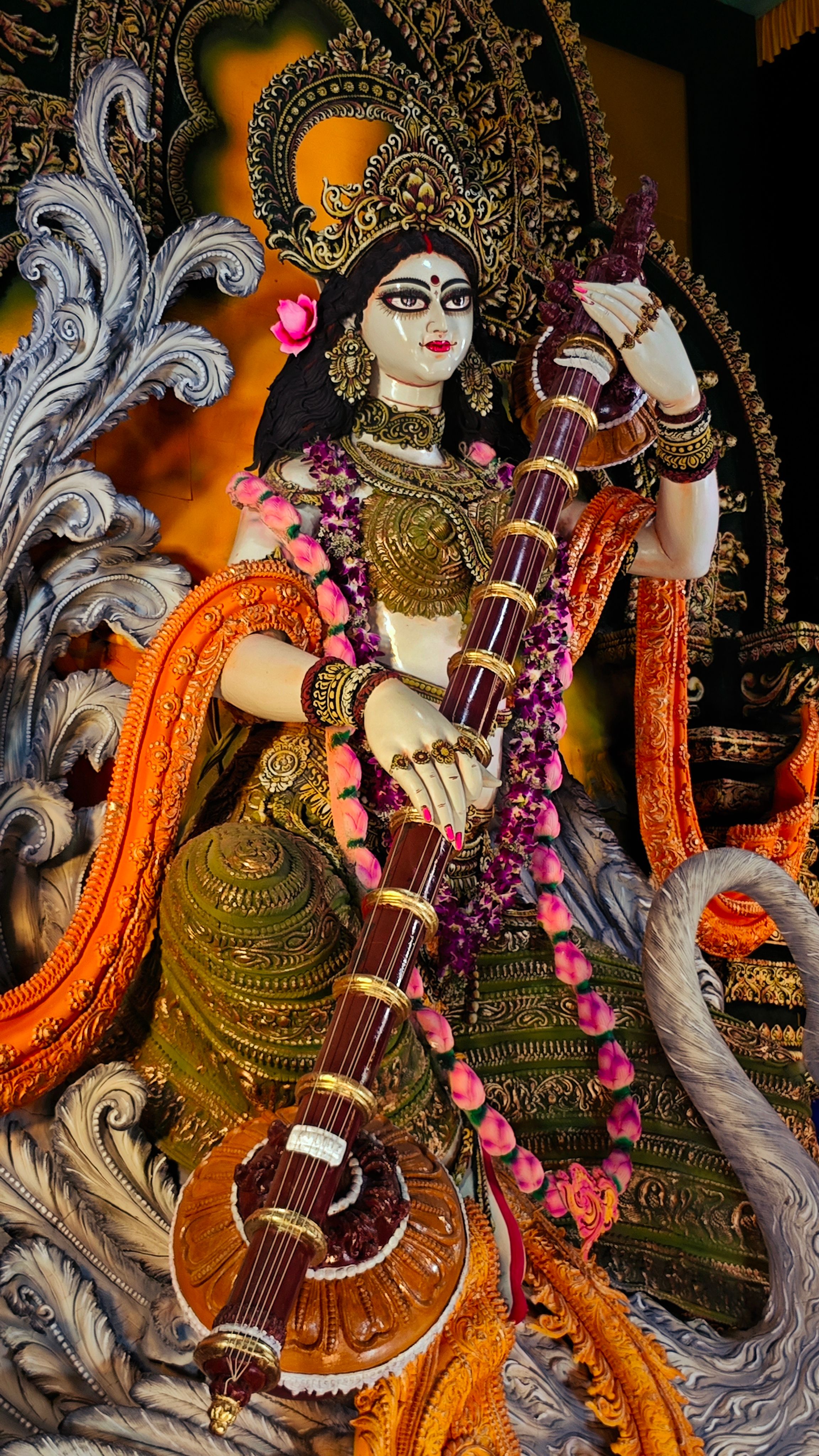 Intricate statue of Indian Goddess Saraswati playing a veena, adorned in traditional attire.