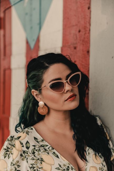 Trendy woman in cat-eye sunglasses poses stylishly against a colorful backdrop.
