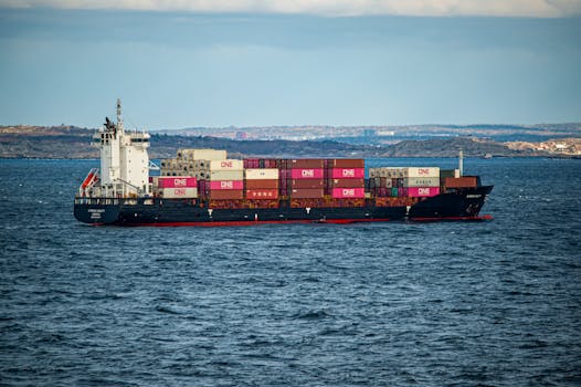 A large container ship transports cargo across the open sea under a clear sky. Ideal for shipping and logistics themes.