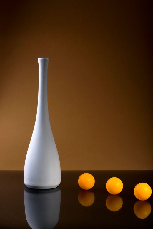 A white vase with orange spheres — Photo by Valentin Ivantsov on Pexels
