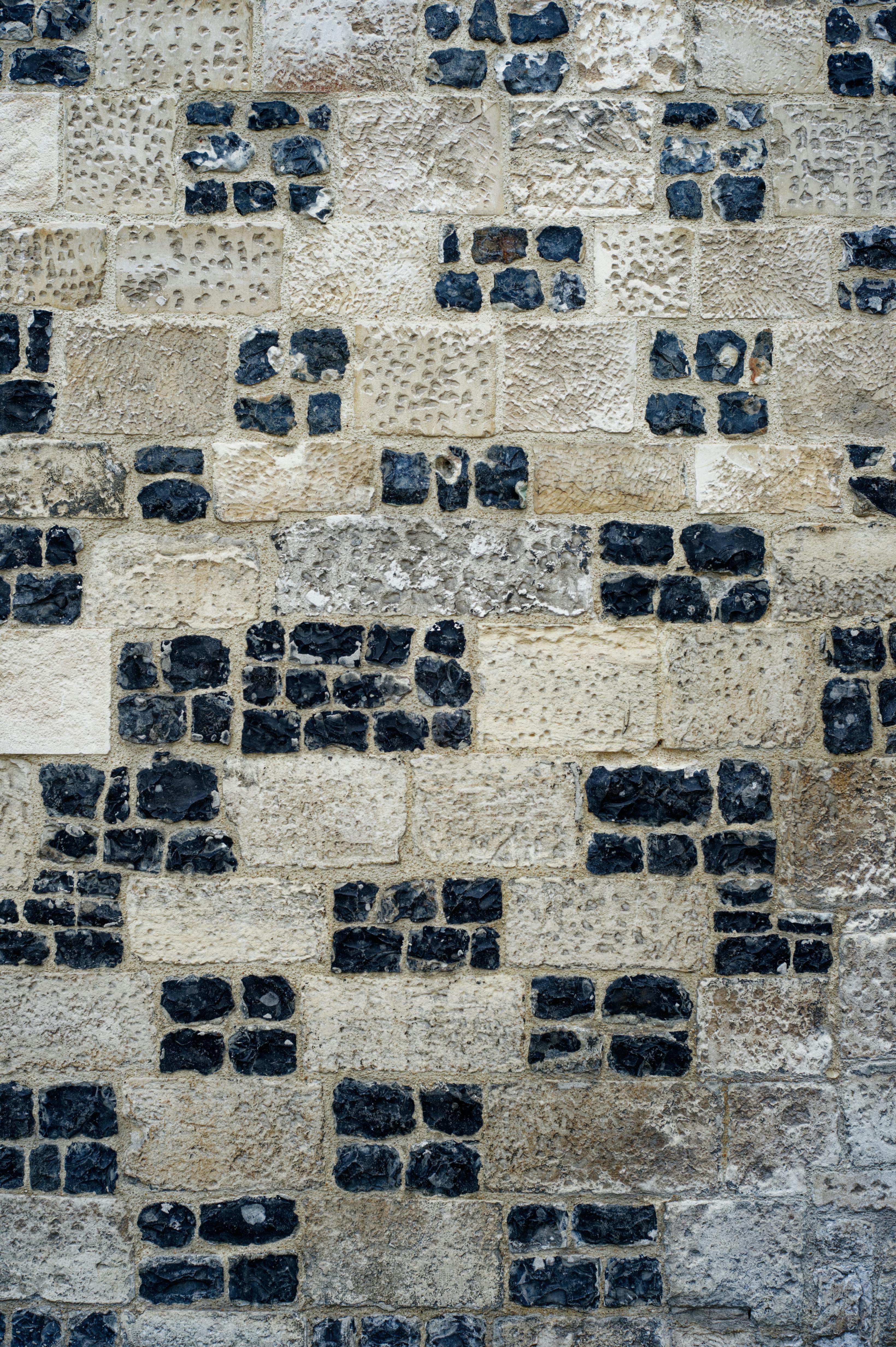 Free Detailed view of a textured stone brick wall with contrasting patterns. Stock Photo