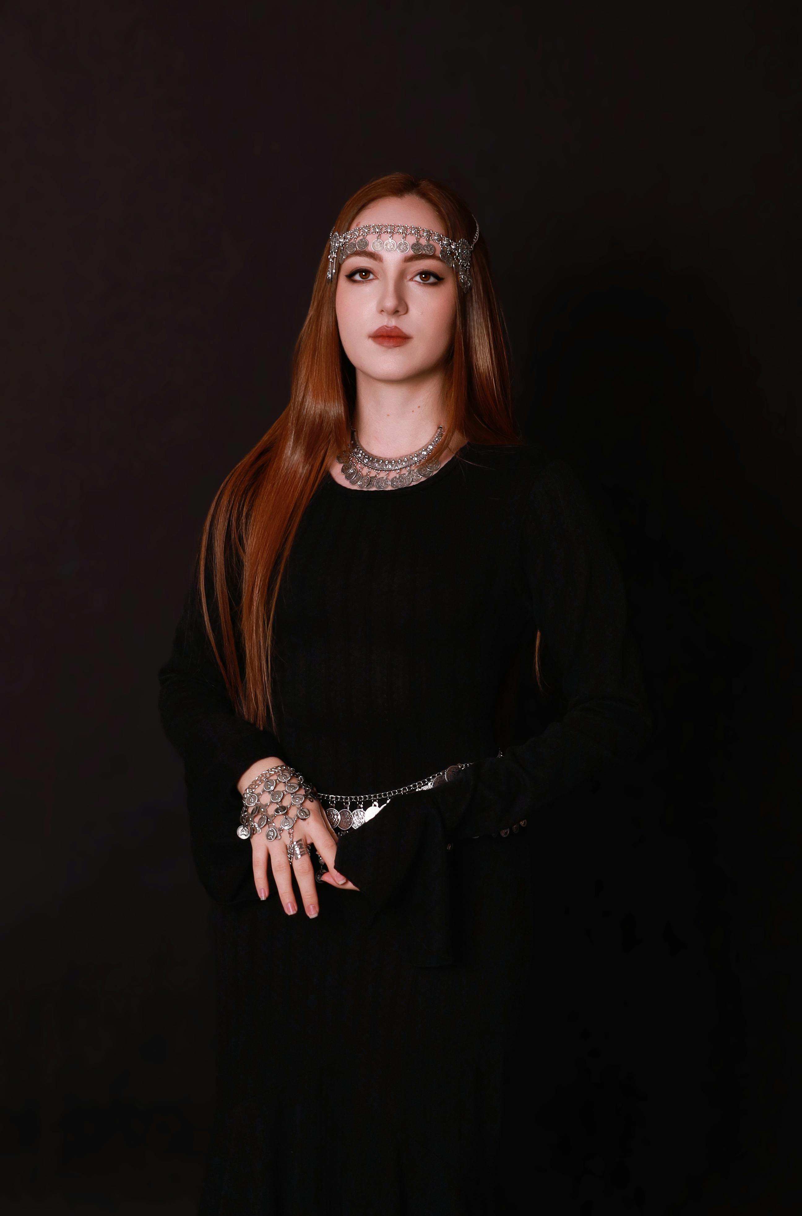 gratis Elegante vrouw in zwarte jurk met sierlijke sieraden, donkere achtergrond. Stockfoto