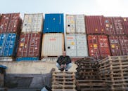 Man crouching near stacked shipping containers