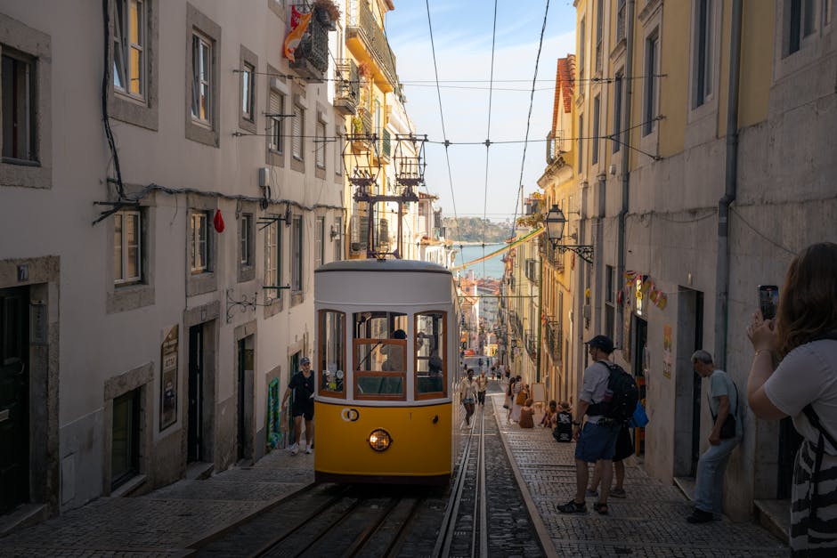 A classic yellow tram navigates a steep street in Lisbon, Portugal, capturing the city's historic charm.