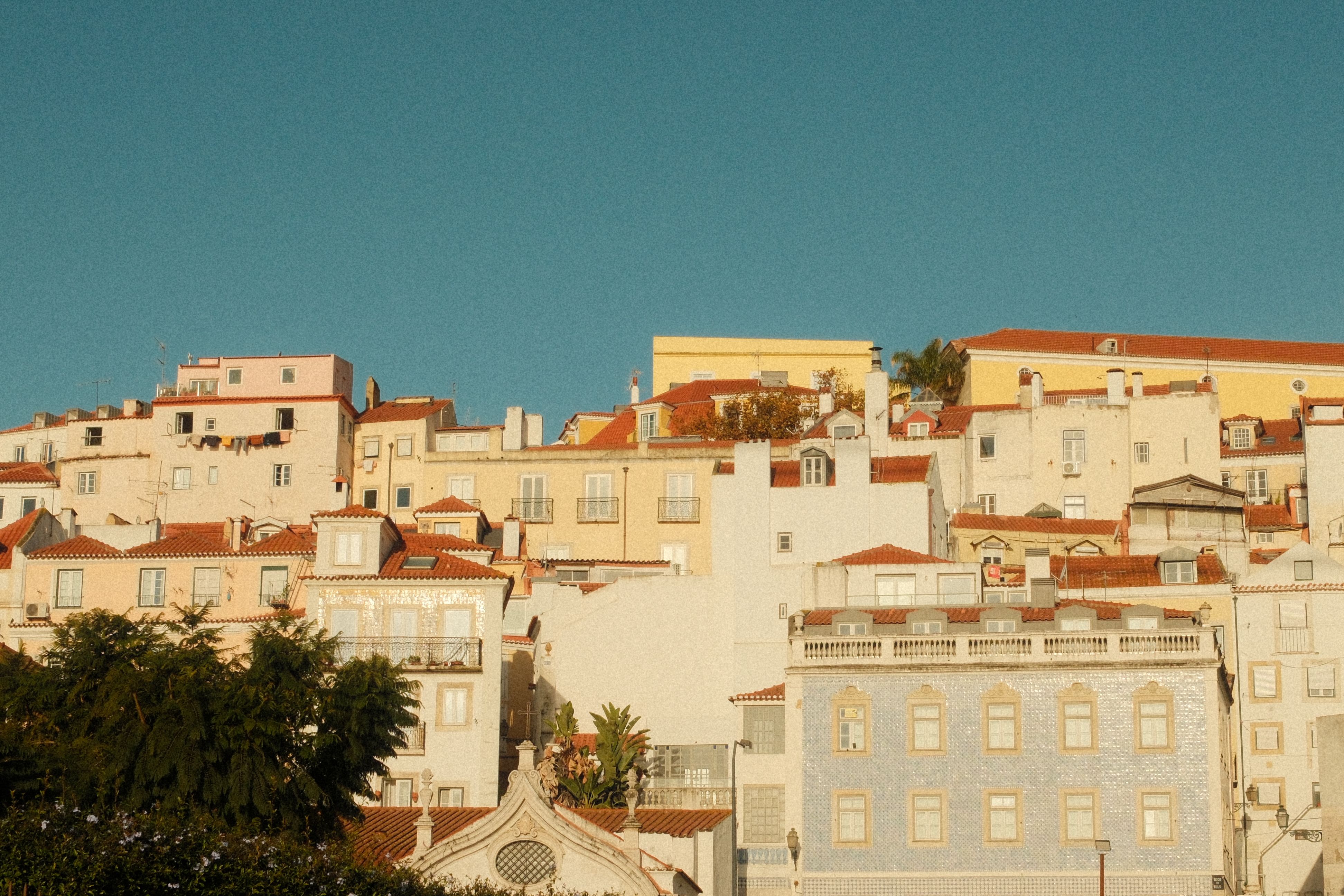 Narrow stepped lane in Alfama with washing lines, tiled facades and the Tejo river below