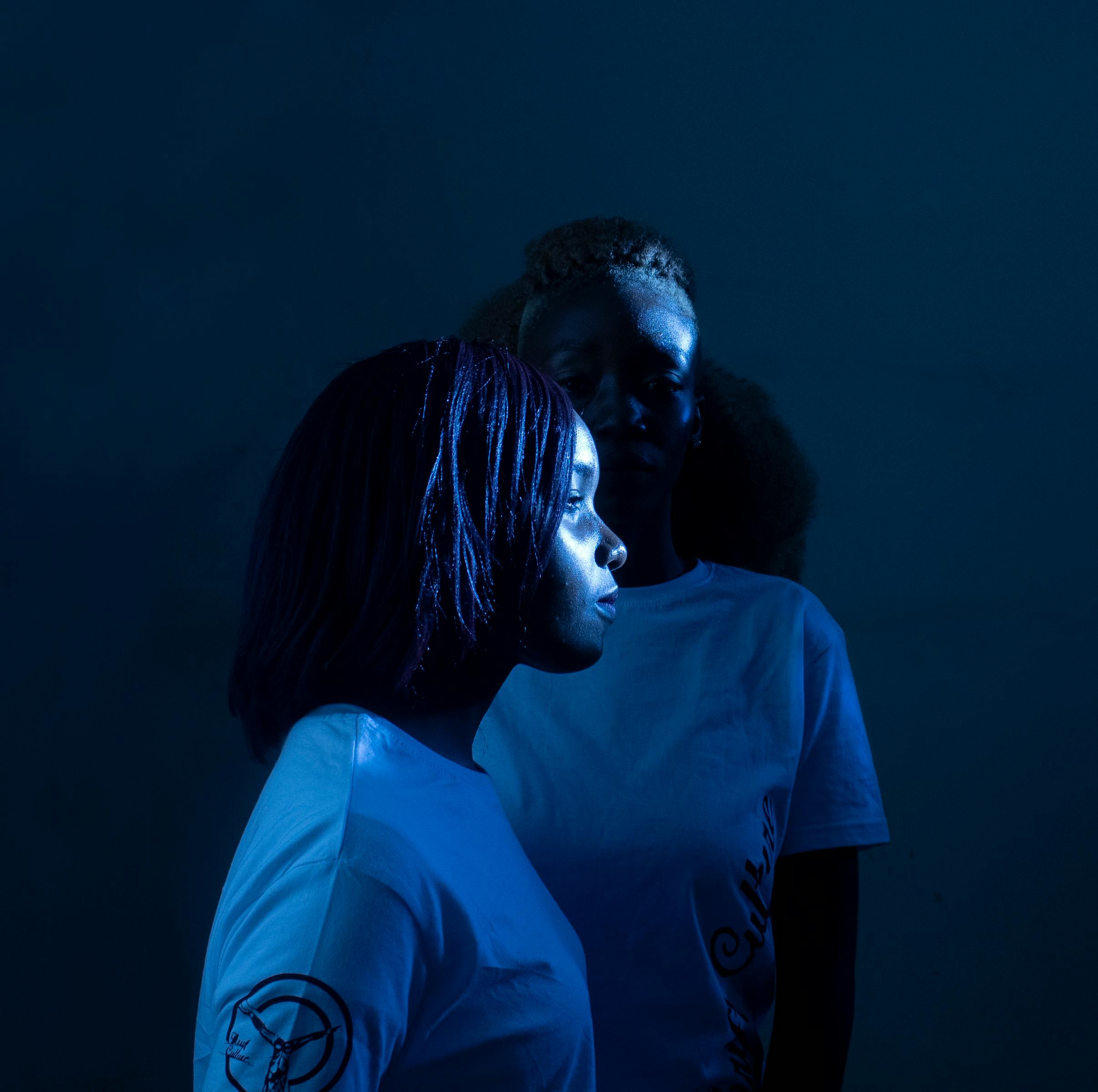 Artistic composition with two women in blue lighting conveying a moody atmosphere.