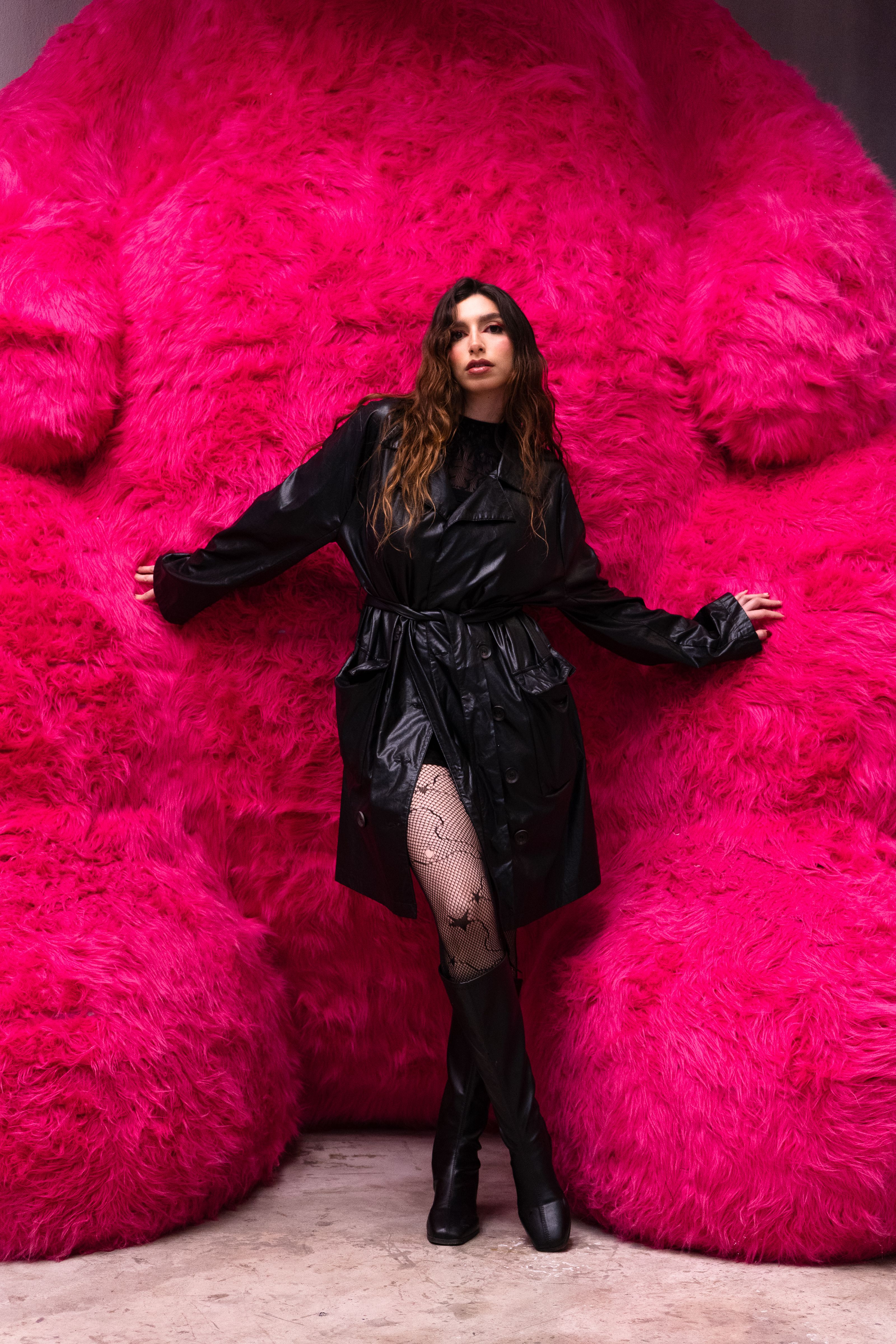 Stylish woman in black outfit posing against large pink sculpture in Mexico City, Mexico.