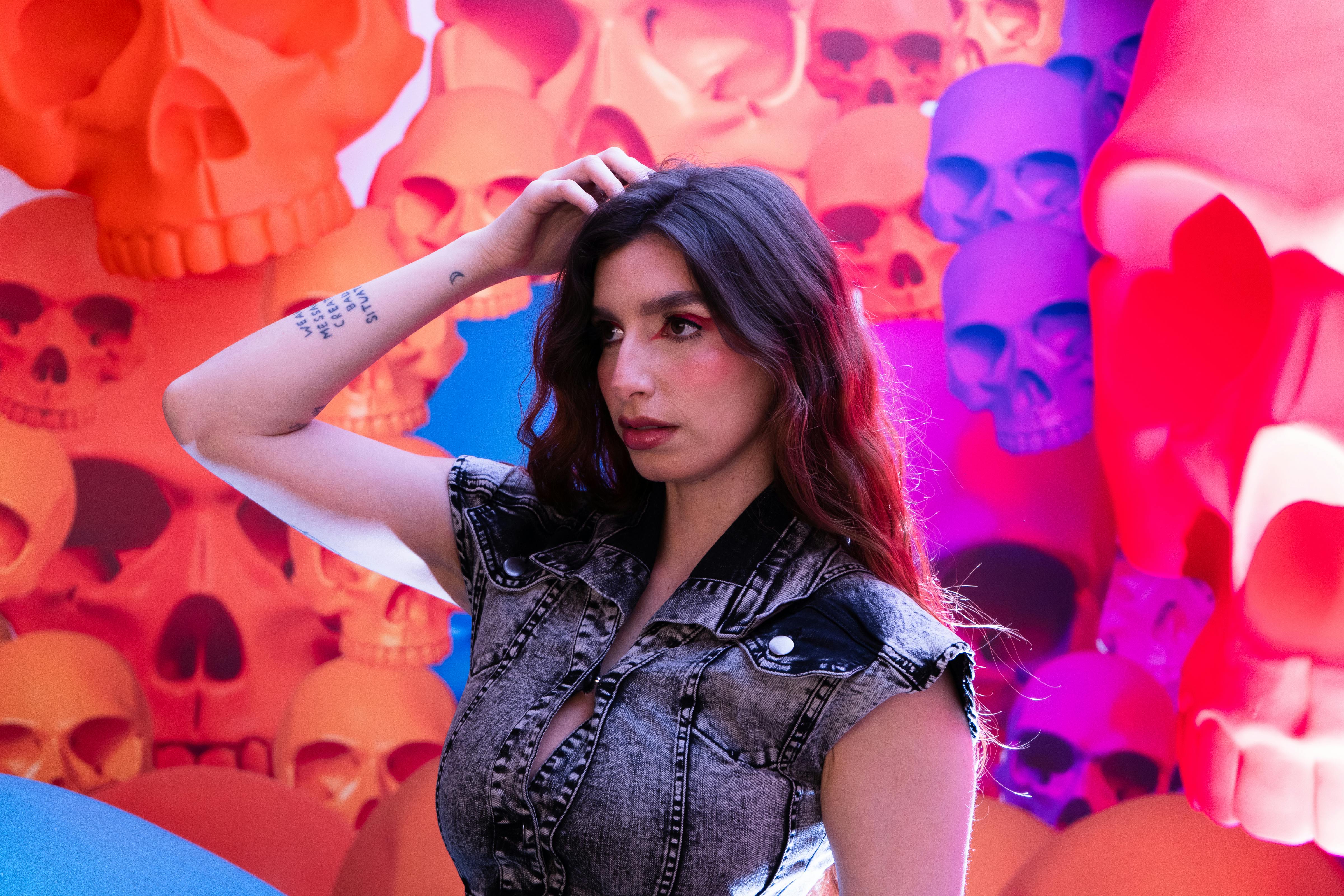 Fashionable woman against colorful skull mural in Mexico City art exhibit.