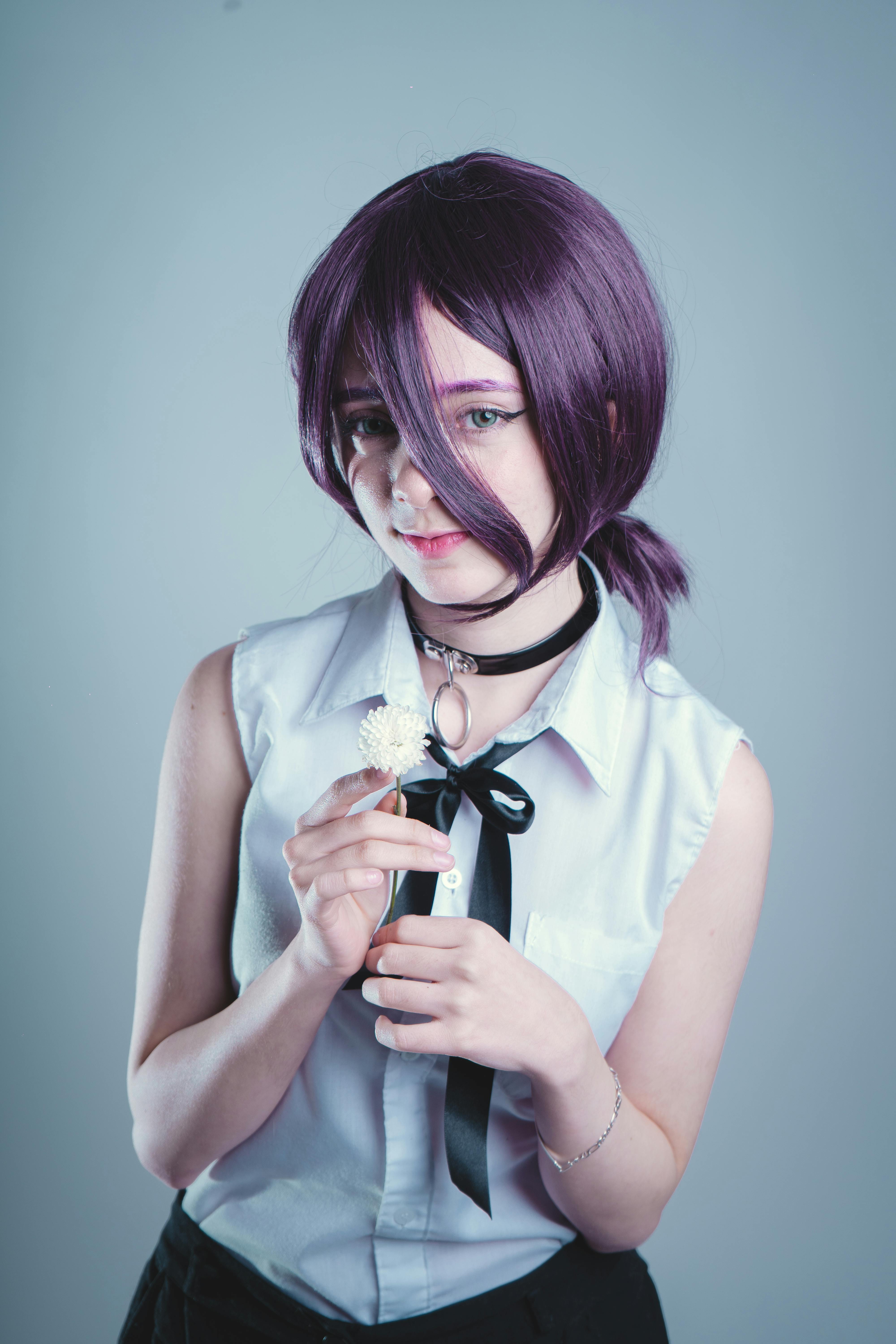 Безкоштовне Молода людина в косплей-одязі тримає білу квітку, у фіолетовому перуку. стокове фото