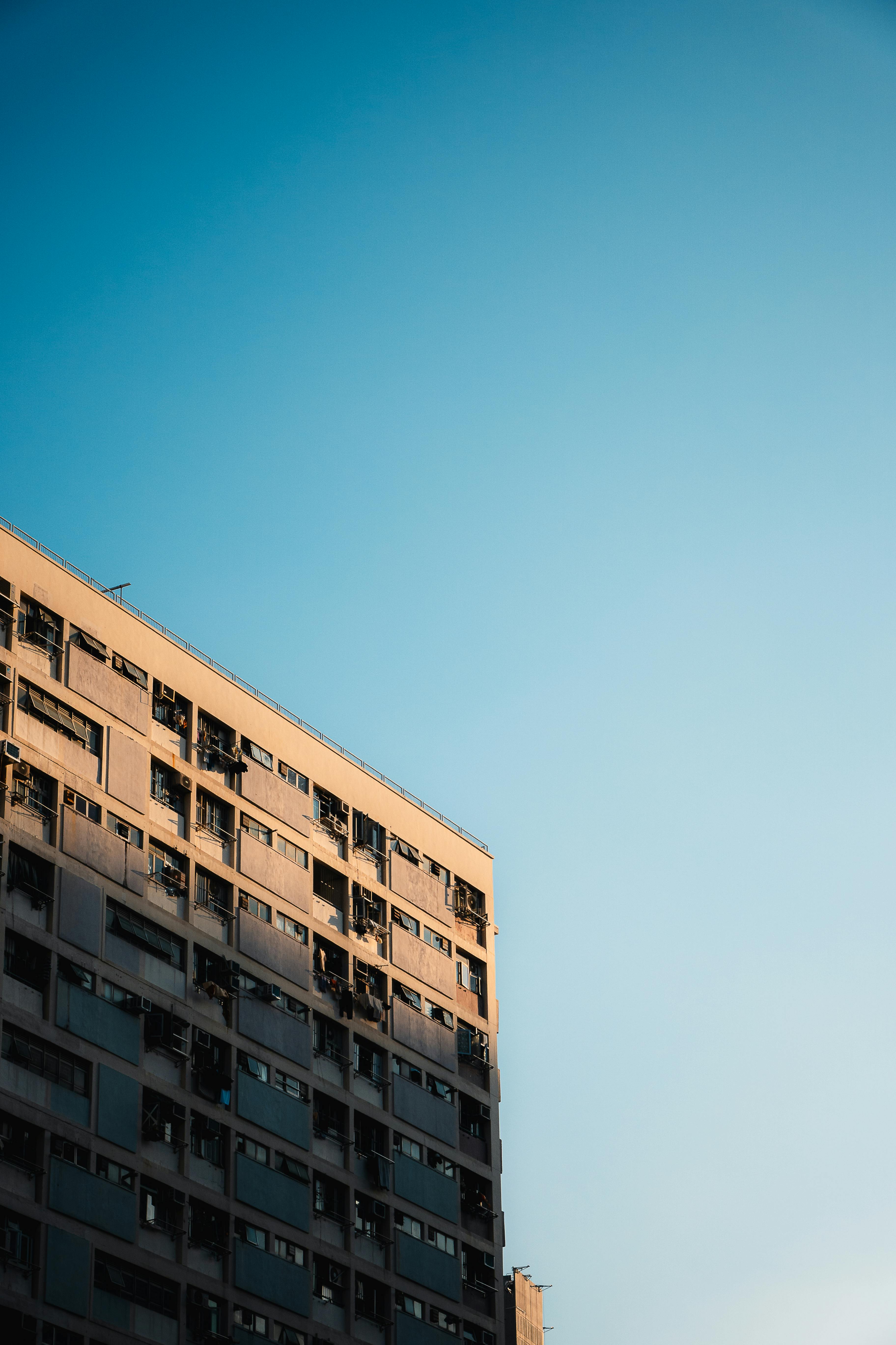 gratis Een hoog gebouw in Kowloon, Hongkong, onder de warme gouden avondhemel, werpt lange schaduwen. Stockfoto