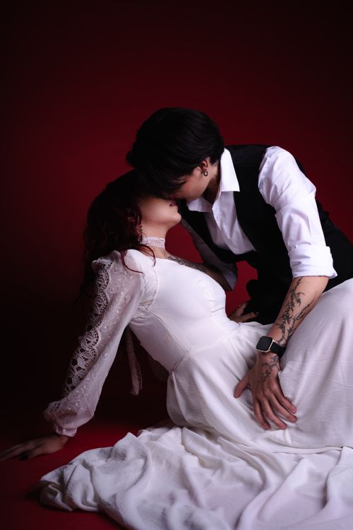Free Elegant couple in a passionate embrace against a deep red background, evoking love and romance. Stock Photo