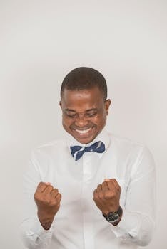 一个开朗的男人穿着时尚的服装，微笑着庆祝成功，显得十分高兴