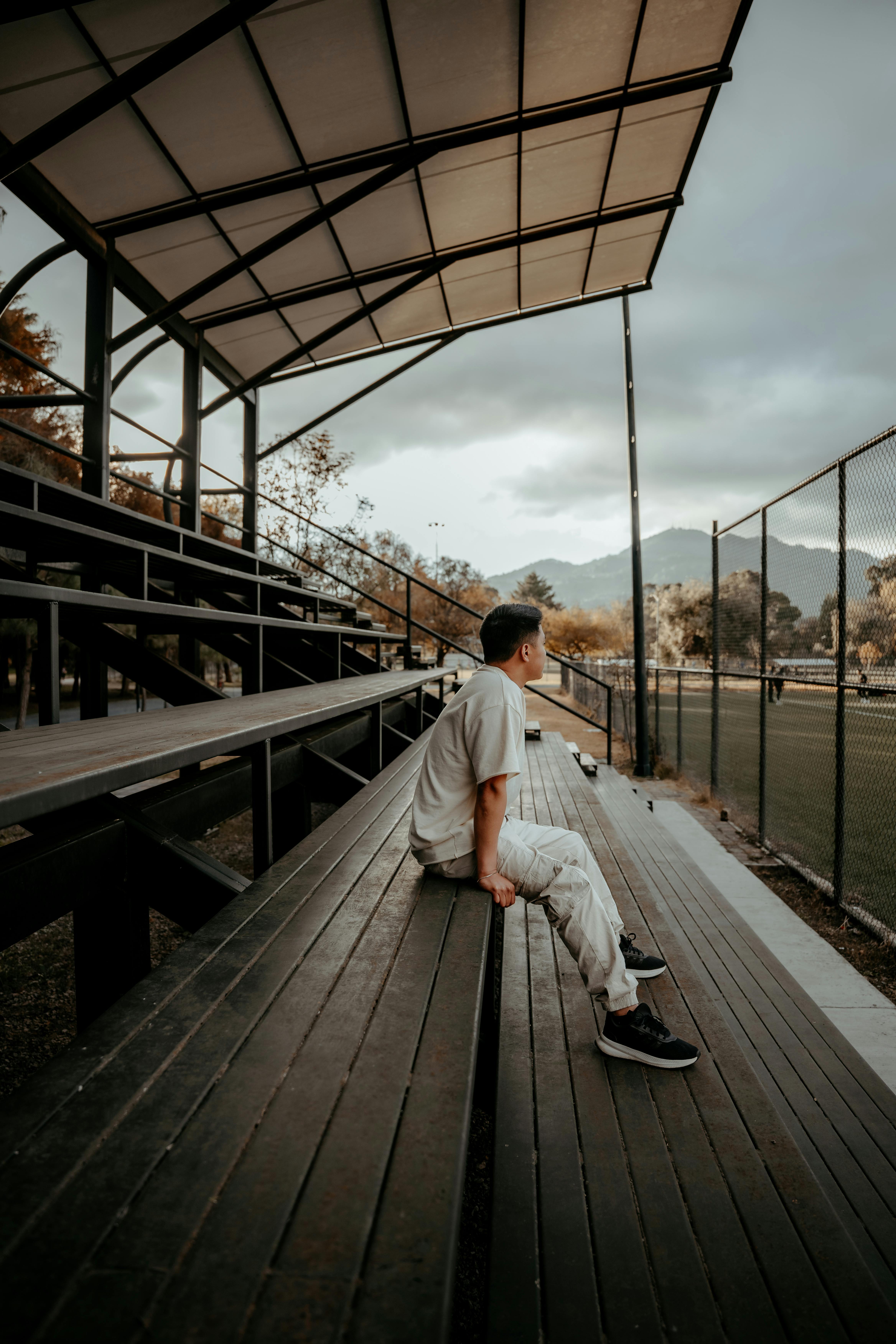 免费 一名男子独自坐在看台上，注视着墨西哥圣克里斯托瓦尔-德拉斯卡萨斯一片寂静的足球场。 素材图片