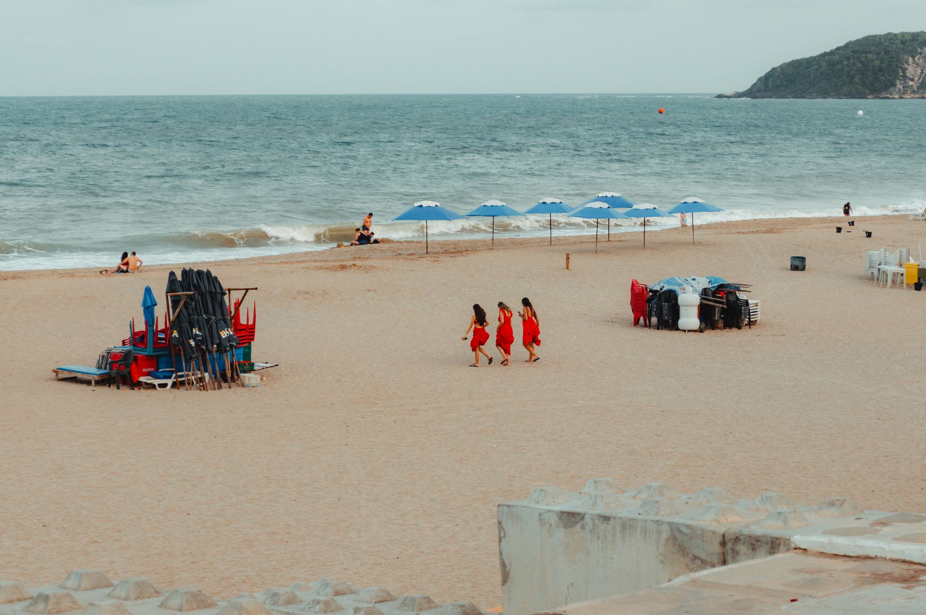 A vibrant beach day in RN, Brazil, with umbrellas and sunbathers under a cloudy sky.