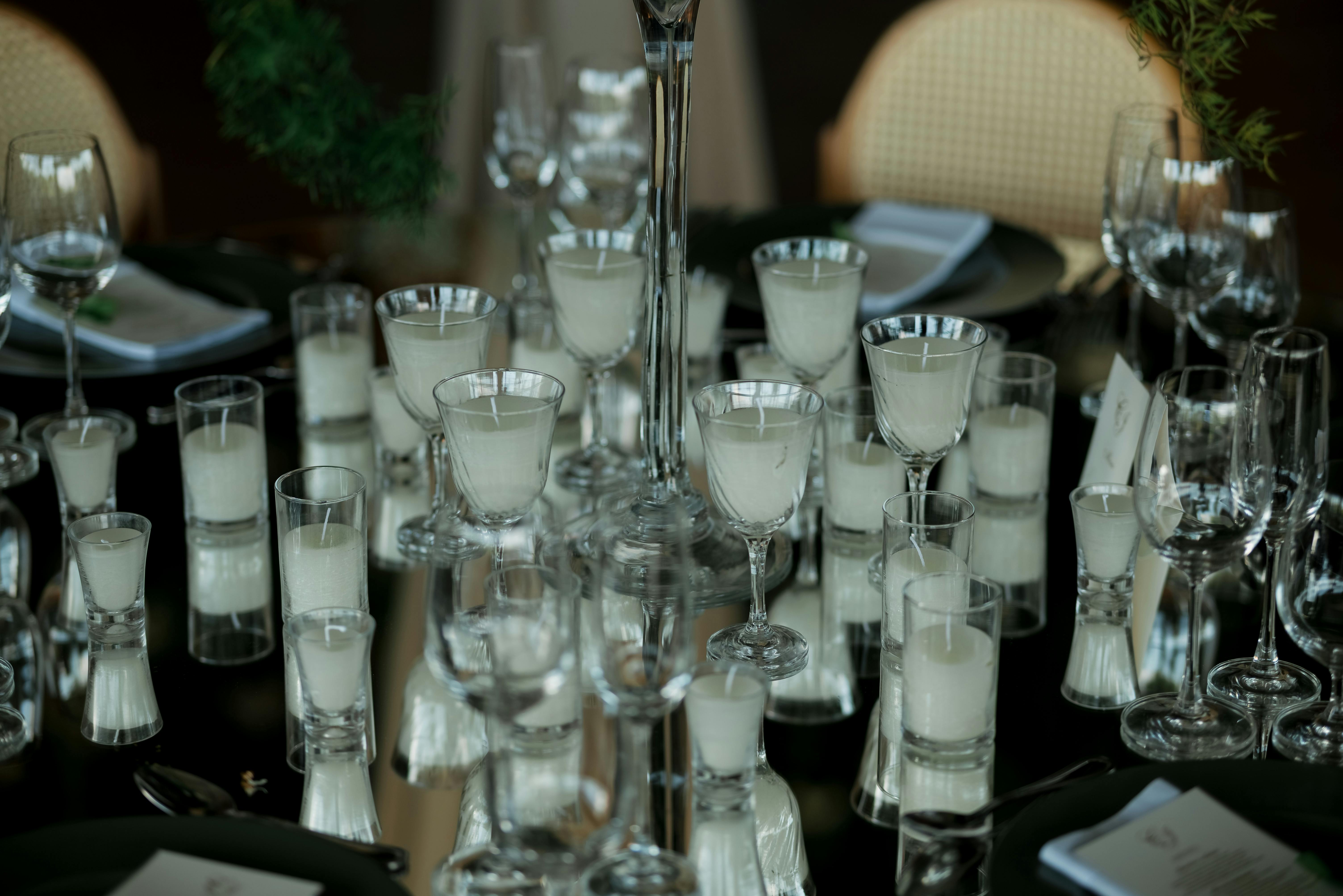 Δωρεάν Ένα εκλεπτυσμένο τραπέζι με κεριά σε γυάλινες θήκες και κομψά γυάλινα σκεύη, δημιουργώντας μια ζεστή, ρομαντική ατμόσφαιρα. Φωτογραφία από στοκ φωτογραφιών