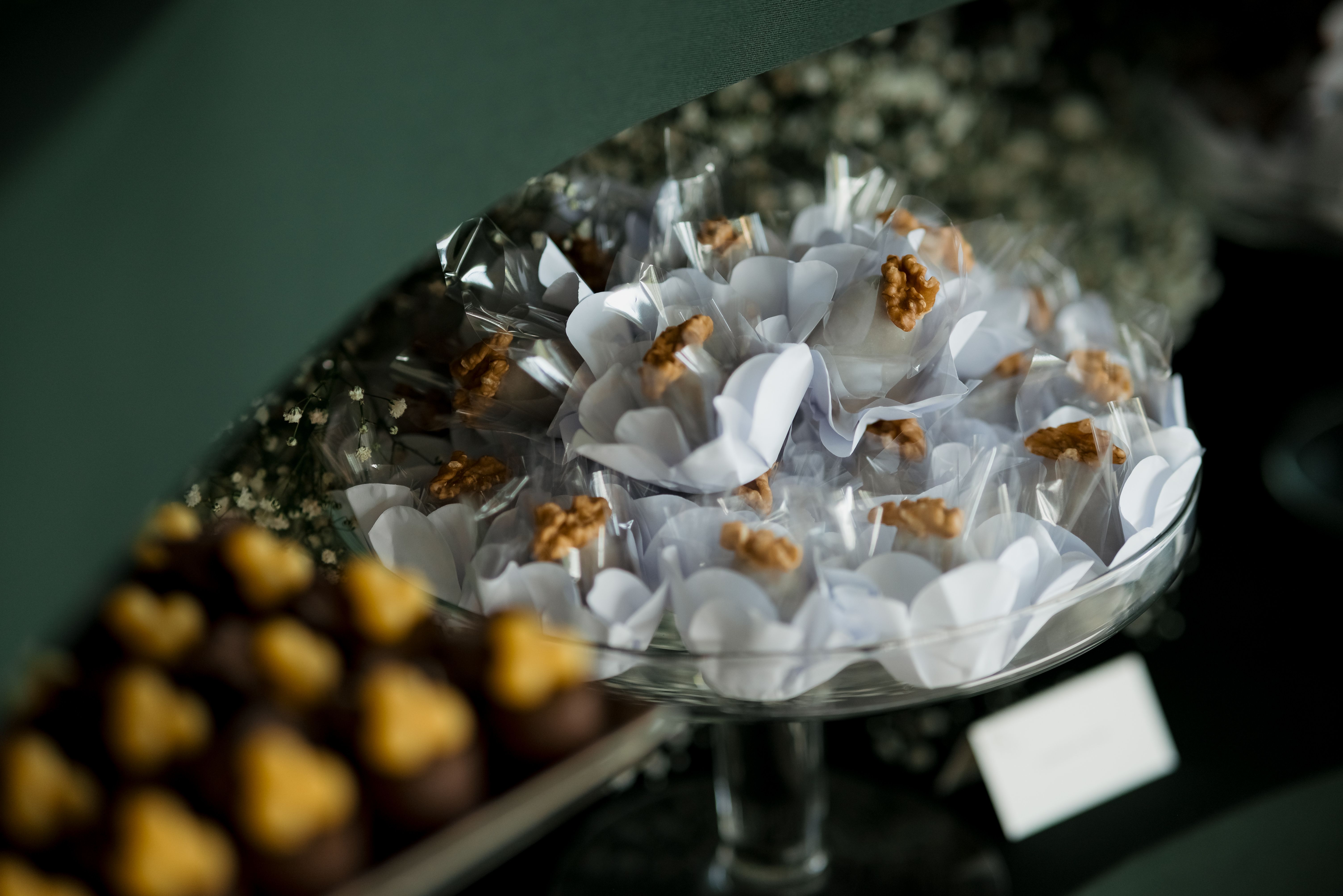 A glass platter showcasing white wrapped confections with walnut toppings, perfect for upscale events.