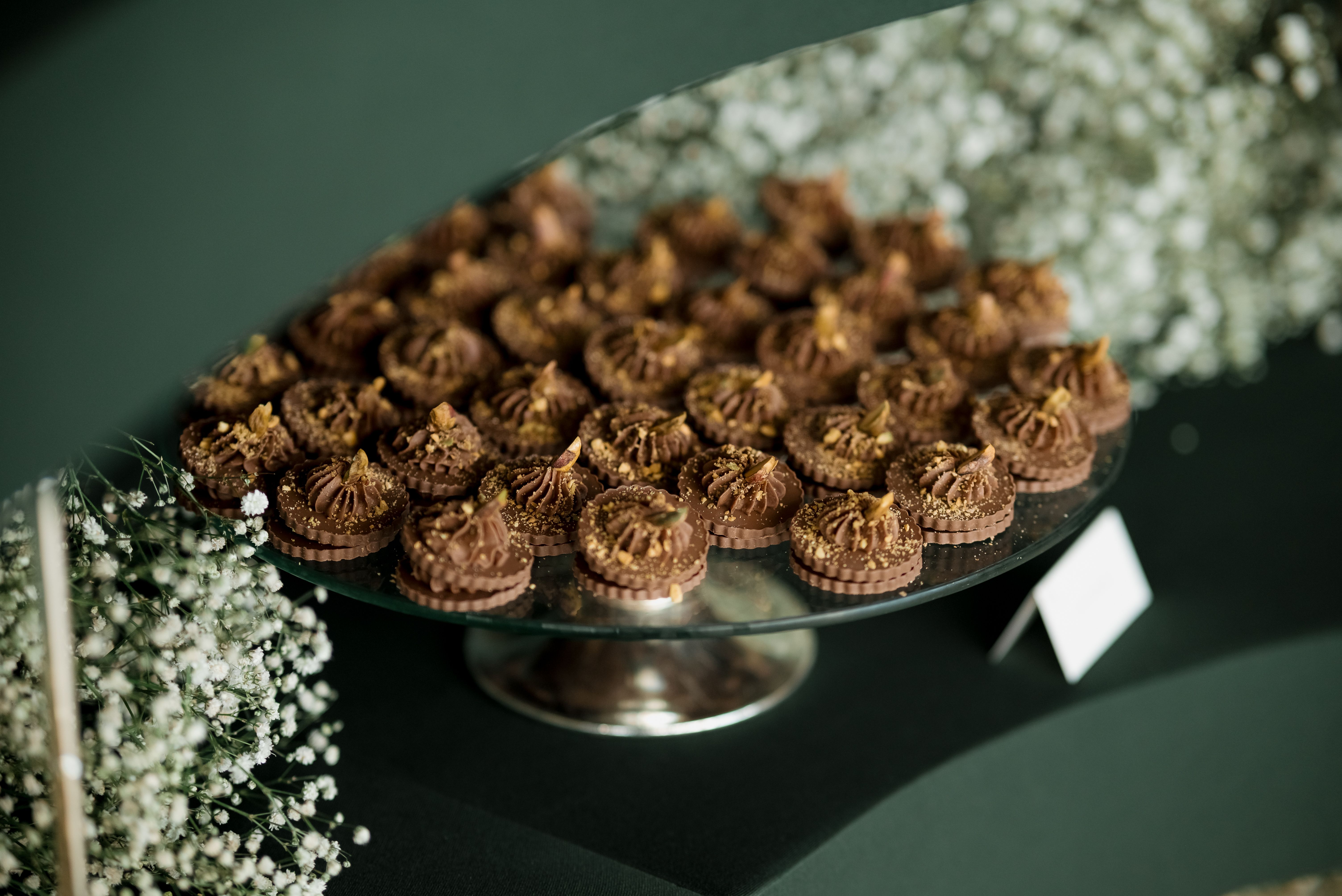 A collection of chocolate desserts elegantly displayed on a mirror tray, accented with delicate flowers.