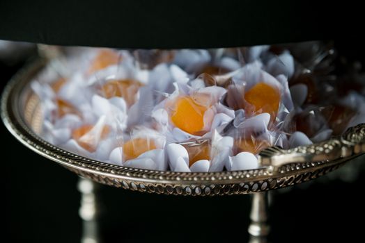 Close-up of vibrant orange candies in elegant packaging on a decorative tray, perfect for gourmet delights. - Fotografer Sidoarjo