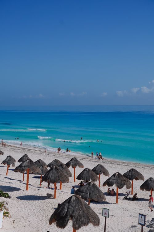 Free Beautiful Cancun beachscape with turquoise waters and thatched umbrellas. Stock Photo