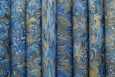 Rolls of hand-marbled endpapers in blue and gold — photo by betül nur akyürek on Pexels