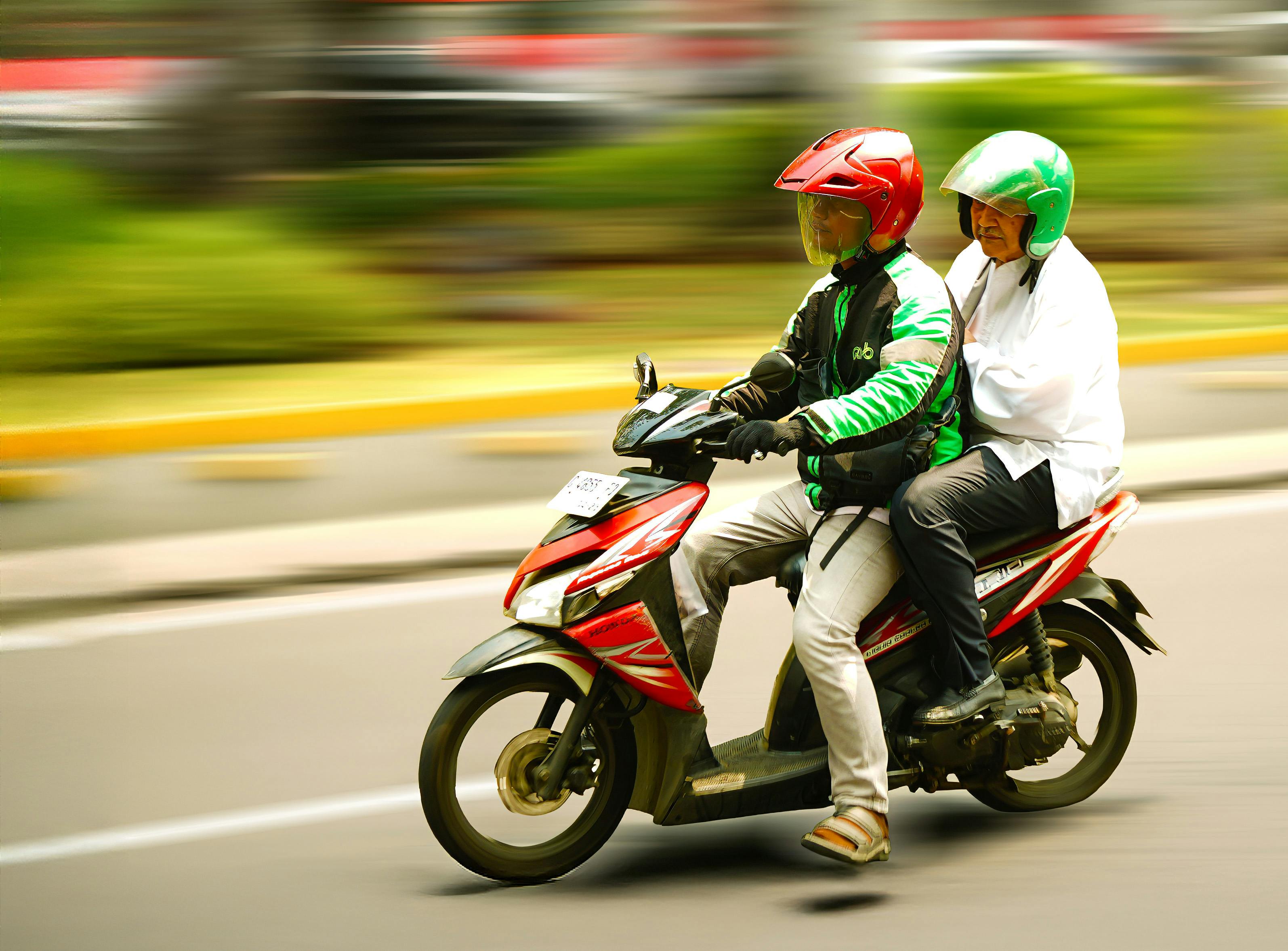 A motorcycle carrying two people speeding through a city street with blurred motion effect.