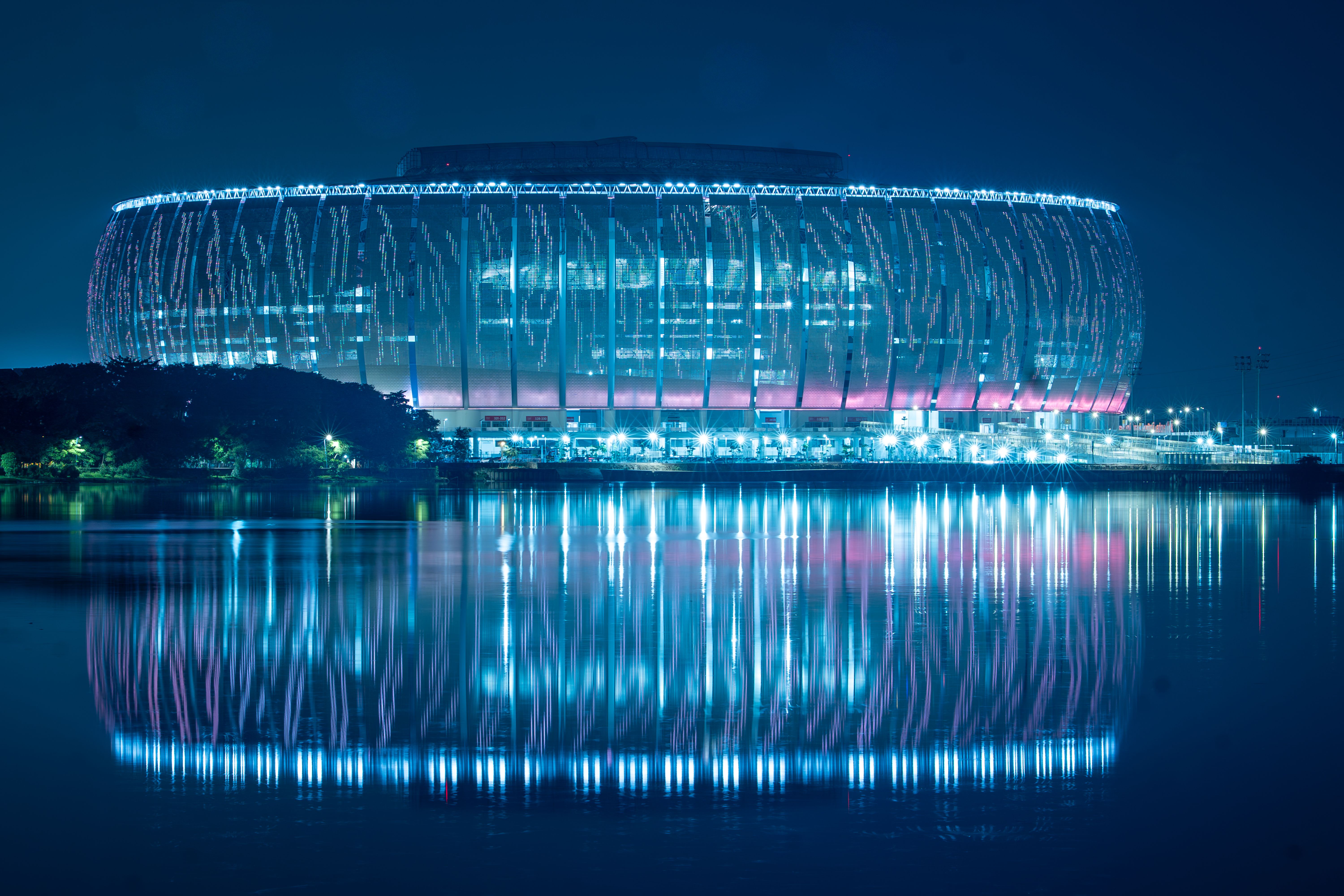 SoFi Stadium glowing under evening lights, surrounded by arriving football supporters before a World Cup match