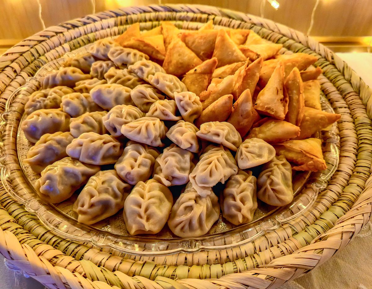Samosas and dumplings on a wicker tray