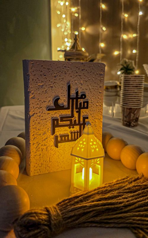 Free Warmly lit scene featuring Arabic calligraphy and a glowing lantern, capturing a festive mood. Stock Photo