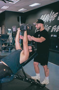 A personal trainer guides a client during a dumbbell workout in a Scottsdale, Arizona gym.