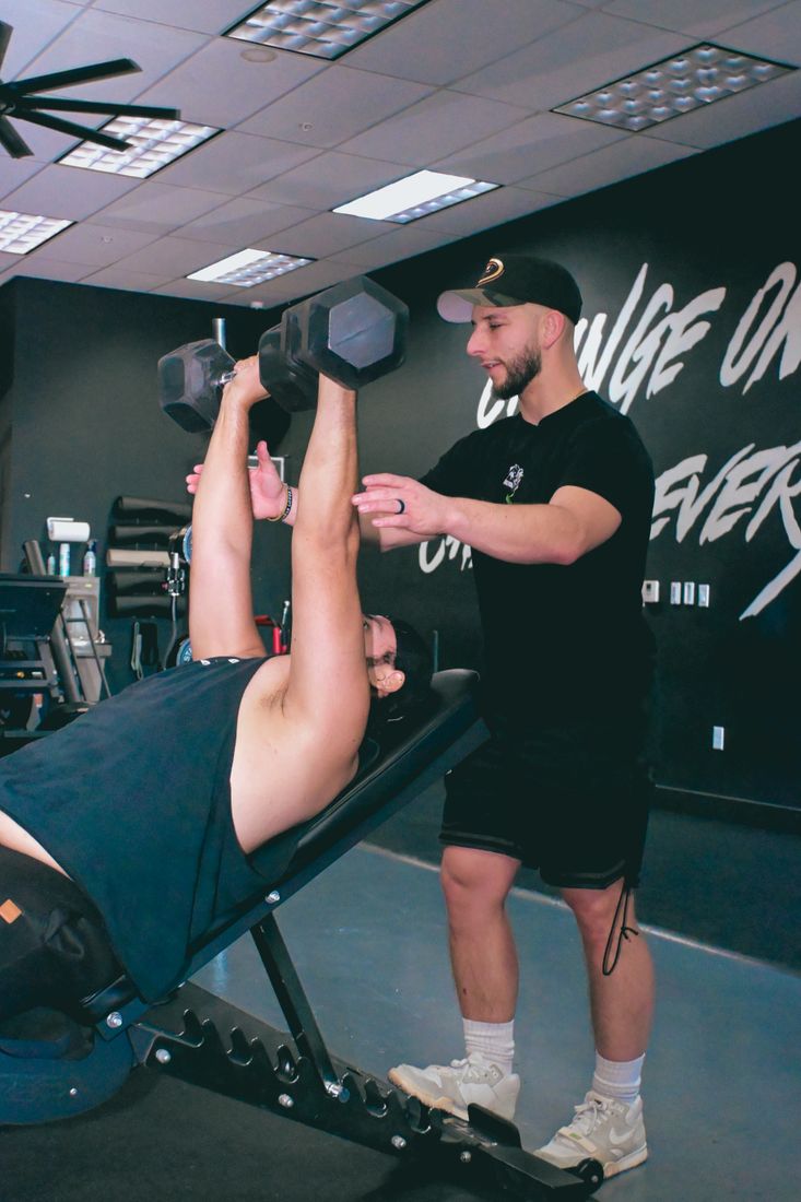 Personal trainer assisting with a dumbbell workout