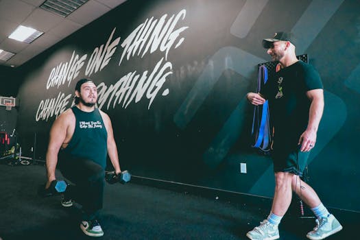 A focused gym session with a coach guiding a man in strength exercises. Motivational environment.