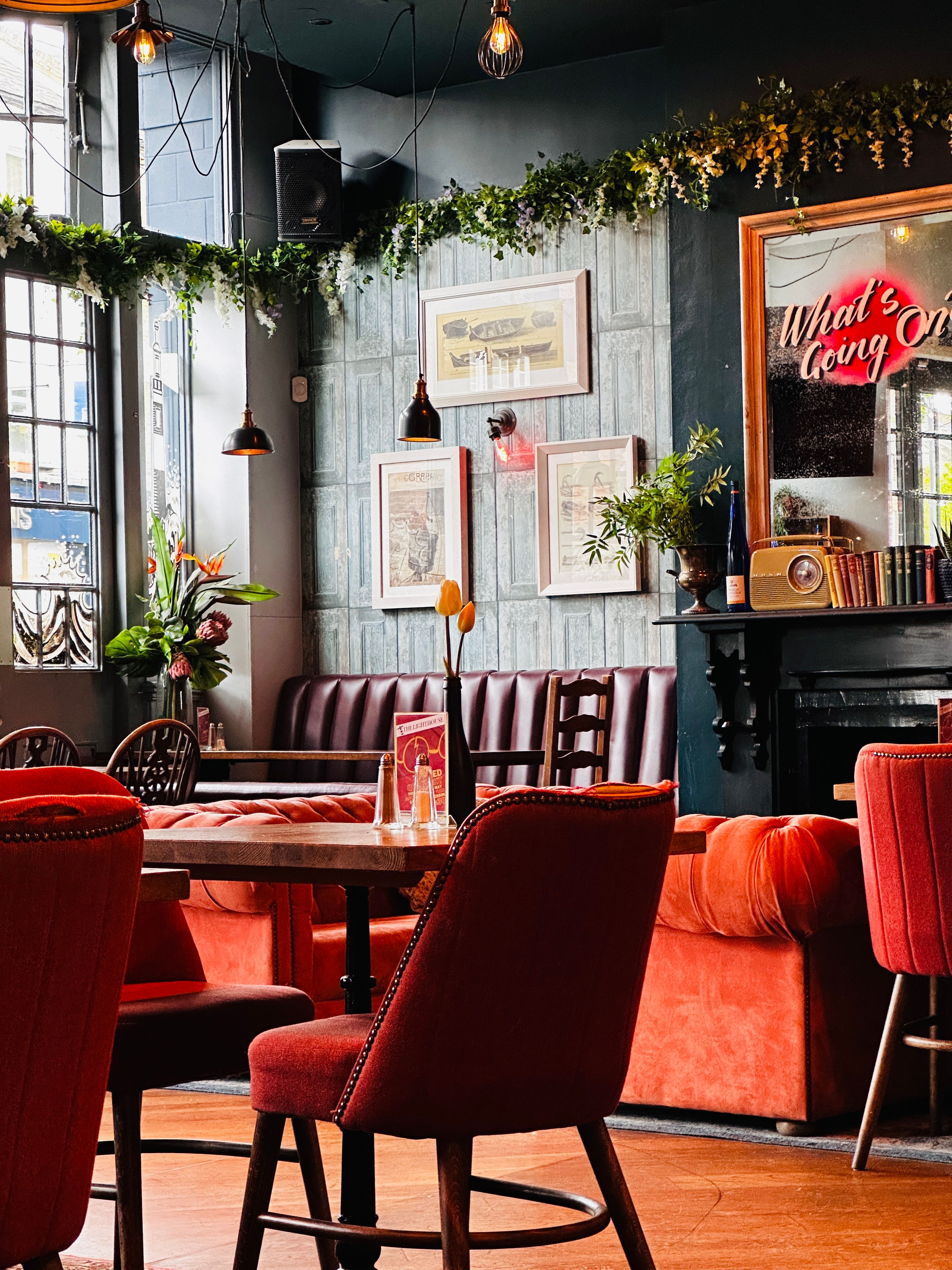 Warm vintage-style cafe interior in London with red seating and botanical decor.