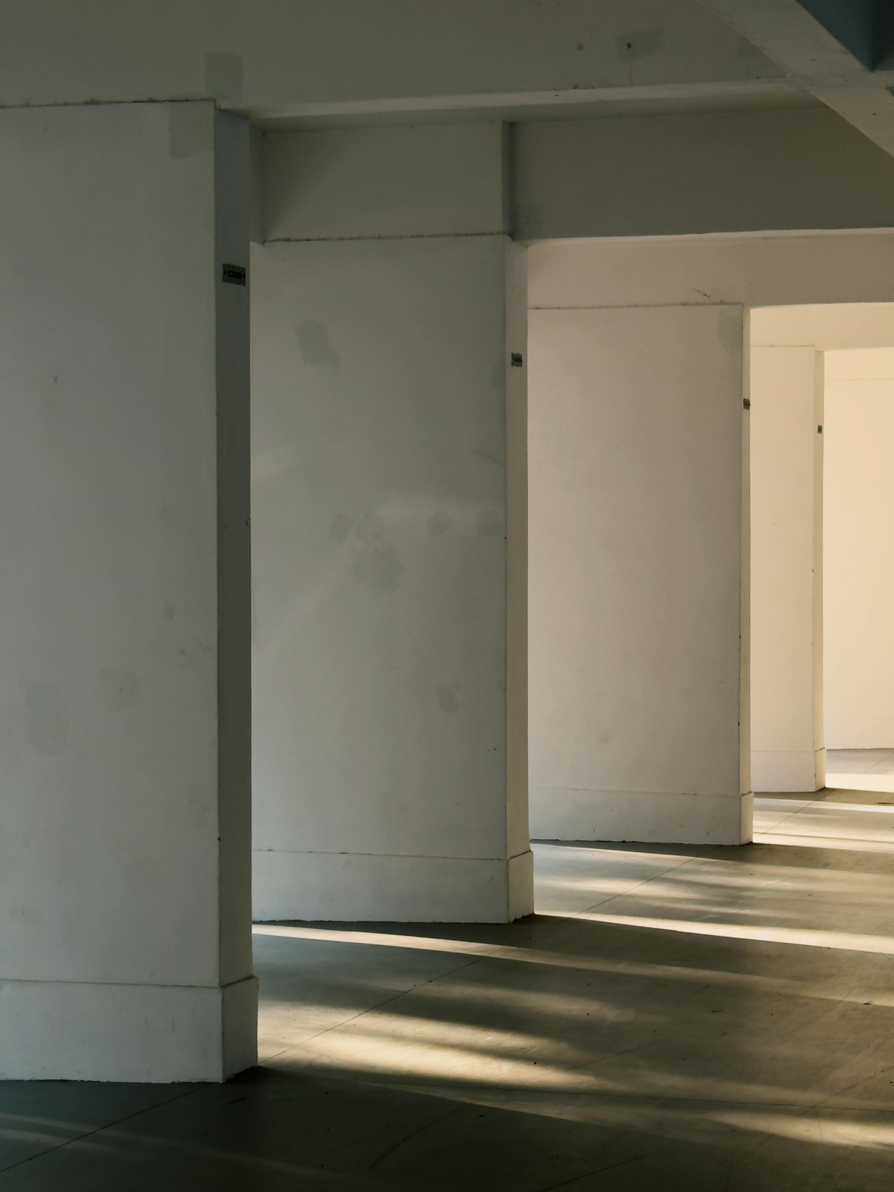 gratis Zonlicht dat door de pilaren in een minimalistisch interieur naar binnen valt, creëert schaduwpatronen. Stockfoto