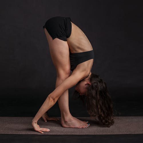 Free Woman Wearing Black Sports Bra Reaching Floor While Standing Stock Photo