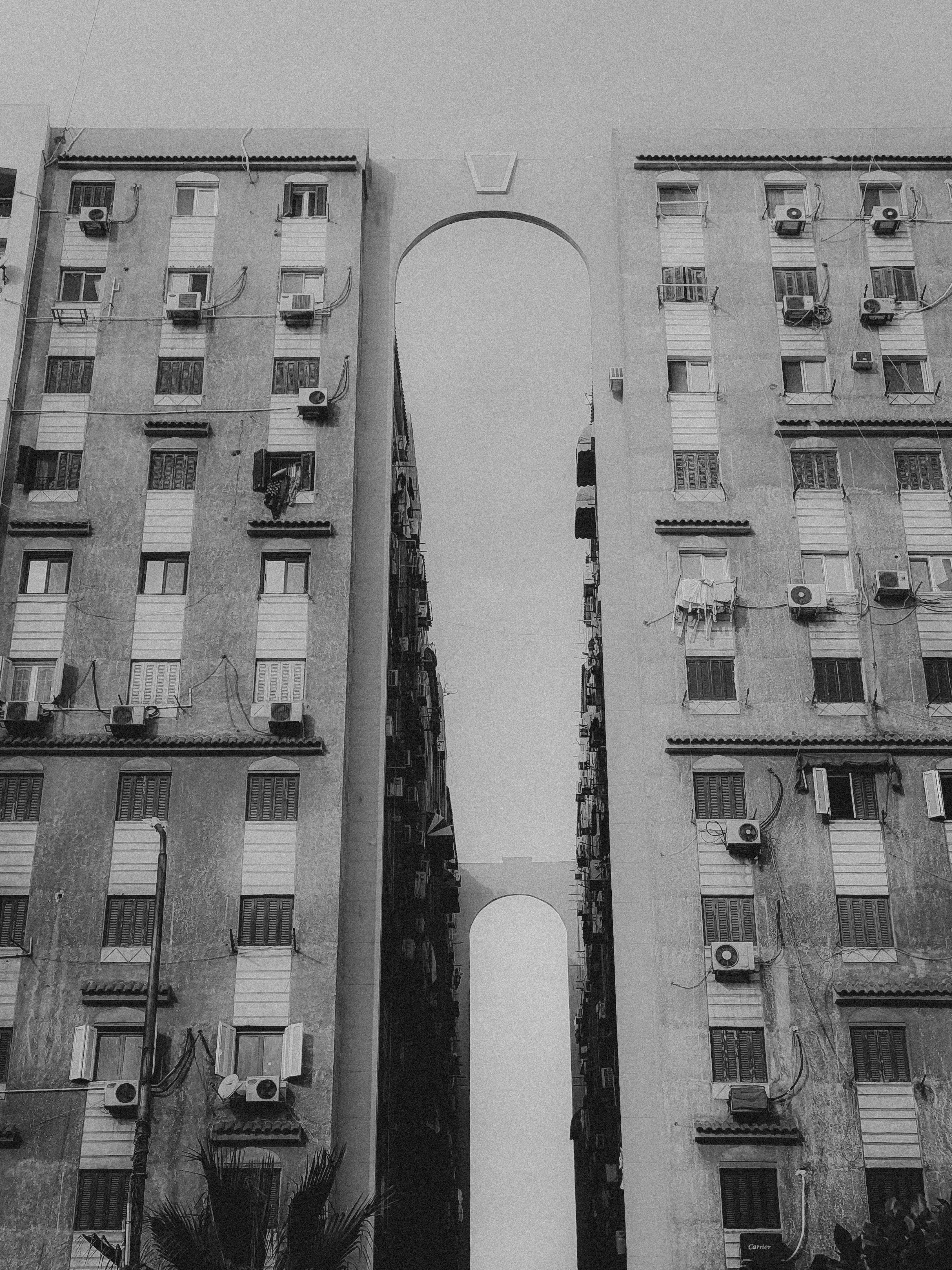 gratis Een opvallende zwart-witfoto van symmetrische stedelijke appartementencomplexen met een boog. Stockfoto