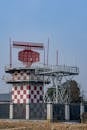 Red and White Radar Tower Against Clear Sky