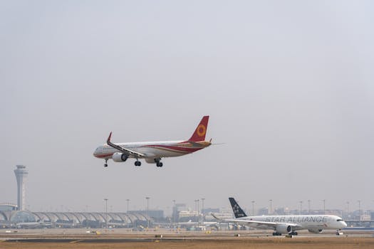 Two commercial airplanes approaching landing at a busy international airport with control tower visible.