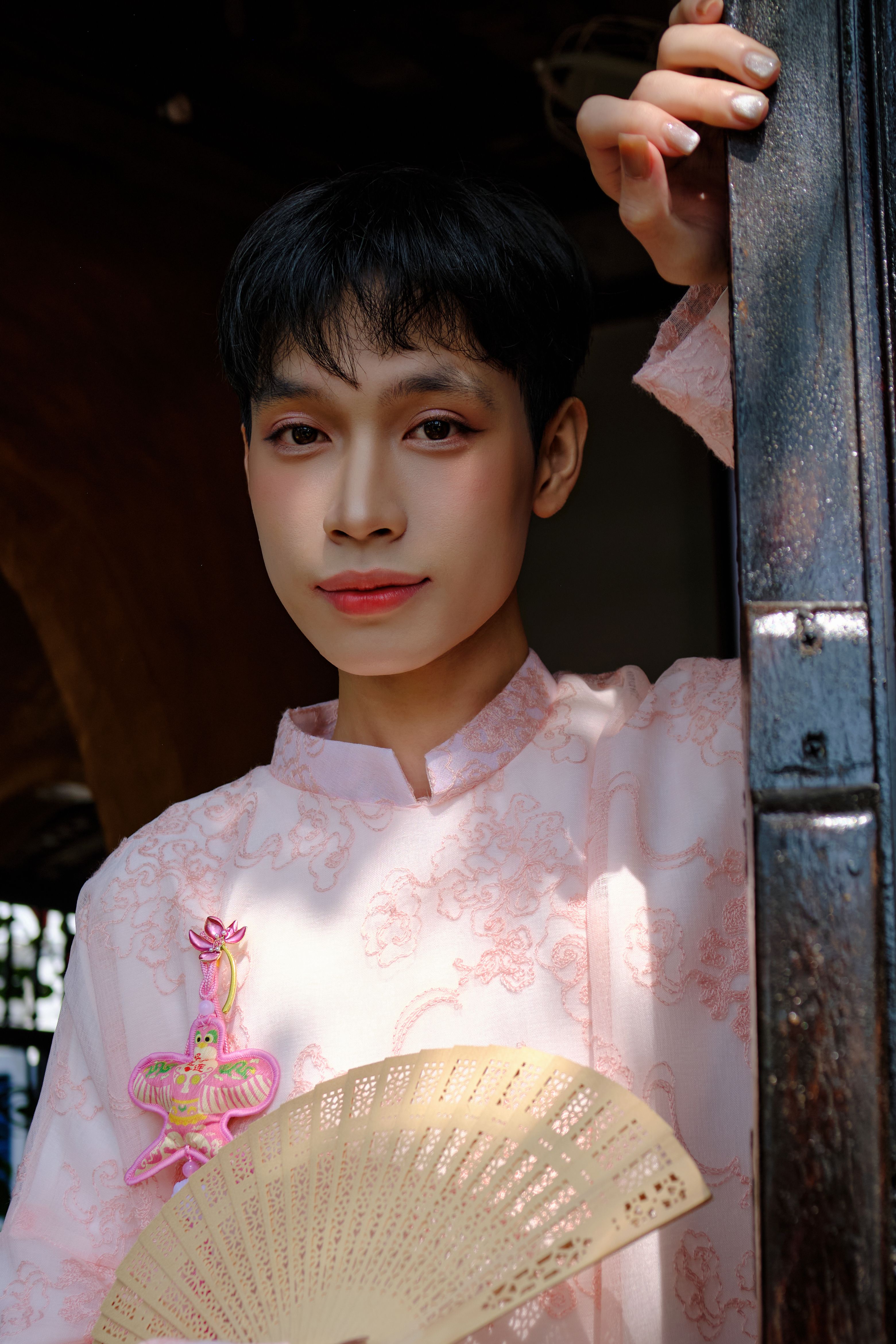 Young man in Ao Dai holding a fan, capturing cultural elegance in Bến Tre, Vietnam.