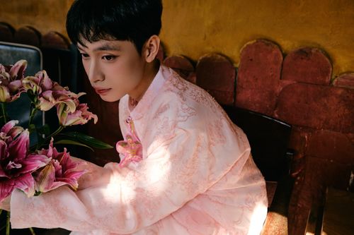 Free A man in a pink Vietnamese Ao Dai holding flowers indoors. Stock Photo