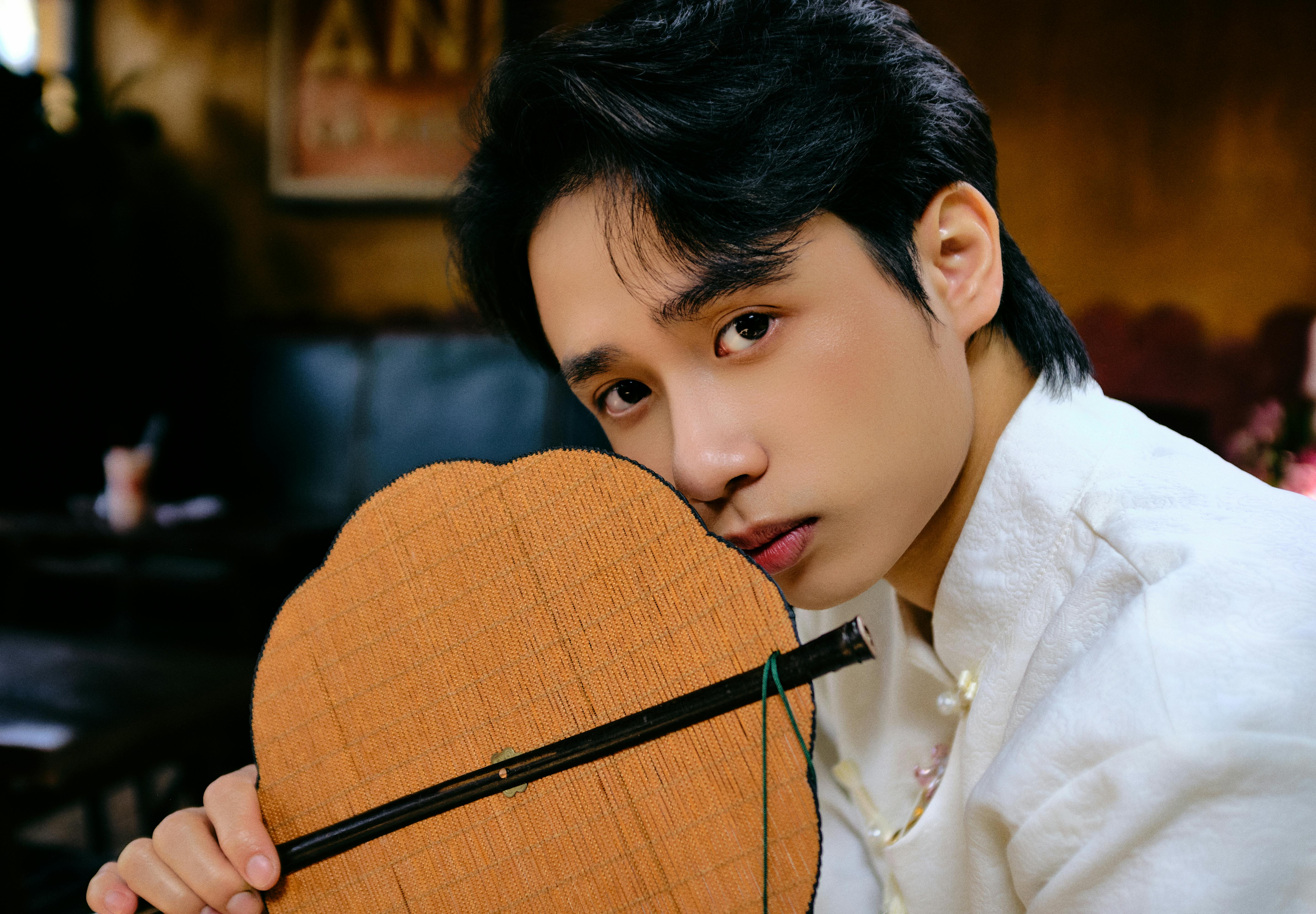 A man in a white ao dai poses indoors, evoking Lunar New Year vibes.