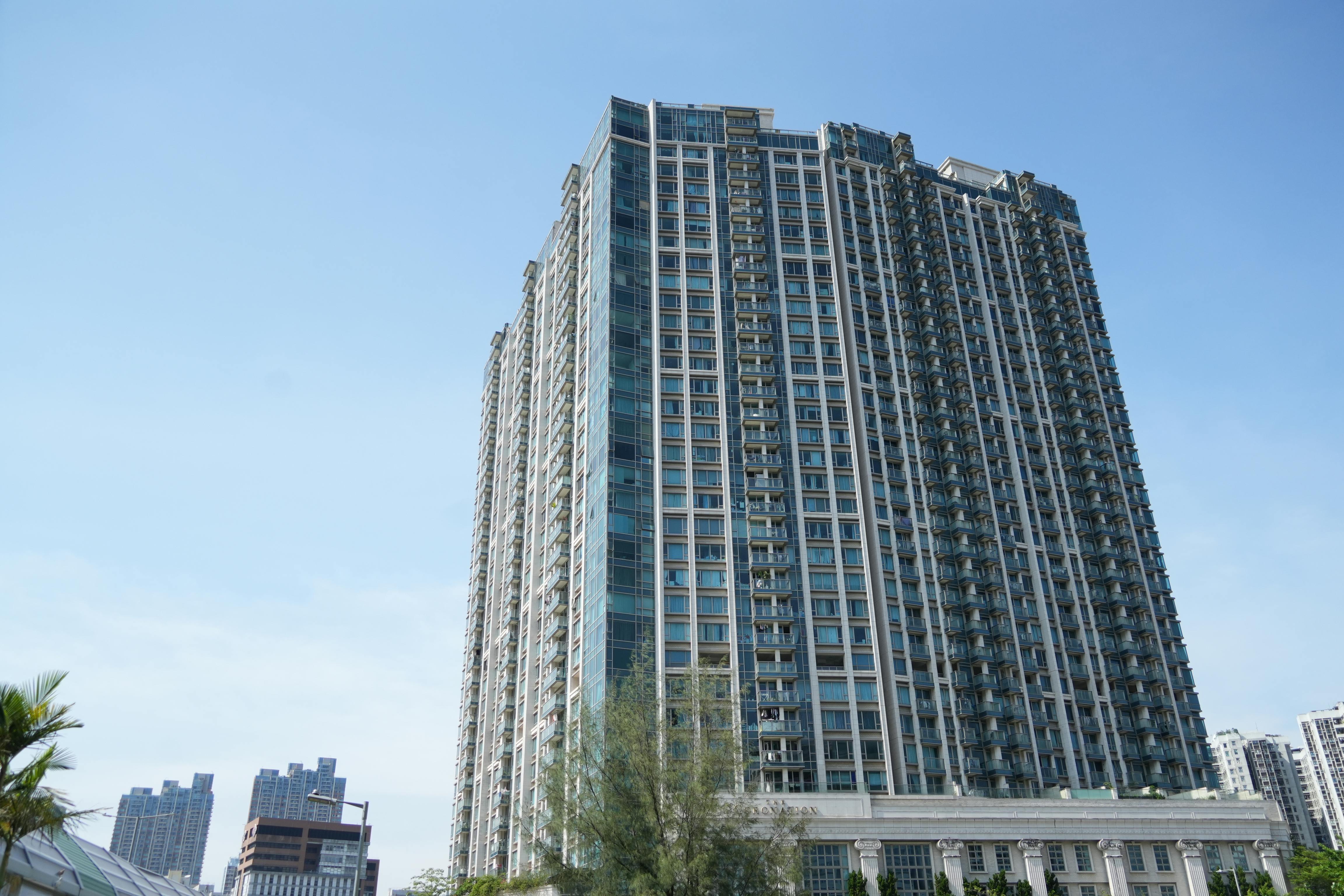 Tall residential skyscraper in Hong Kong against a clear blue sky, showcasing modern architecture.
