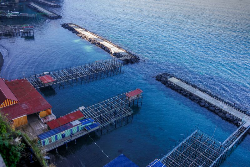 A scenic aerial view of coastal fishing piers with vibrant colors and serene waters, captured at dawn.