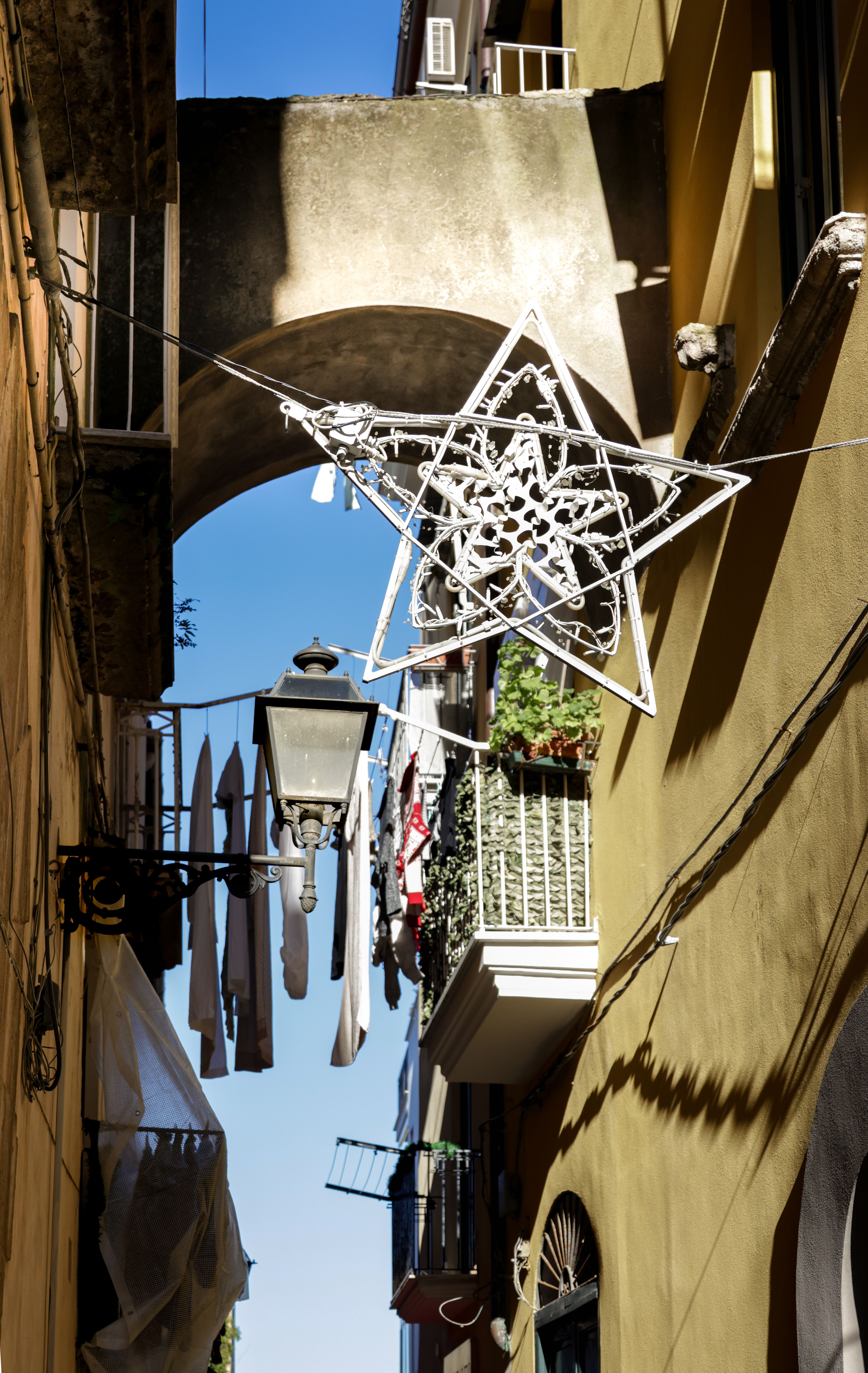 A sunlit alley in Italy features a star decoration and traditional architecture.