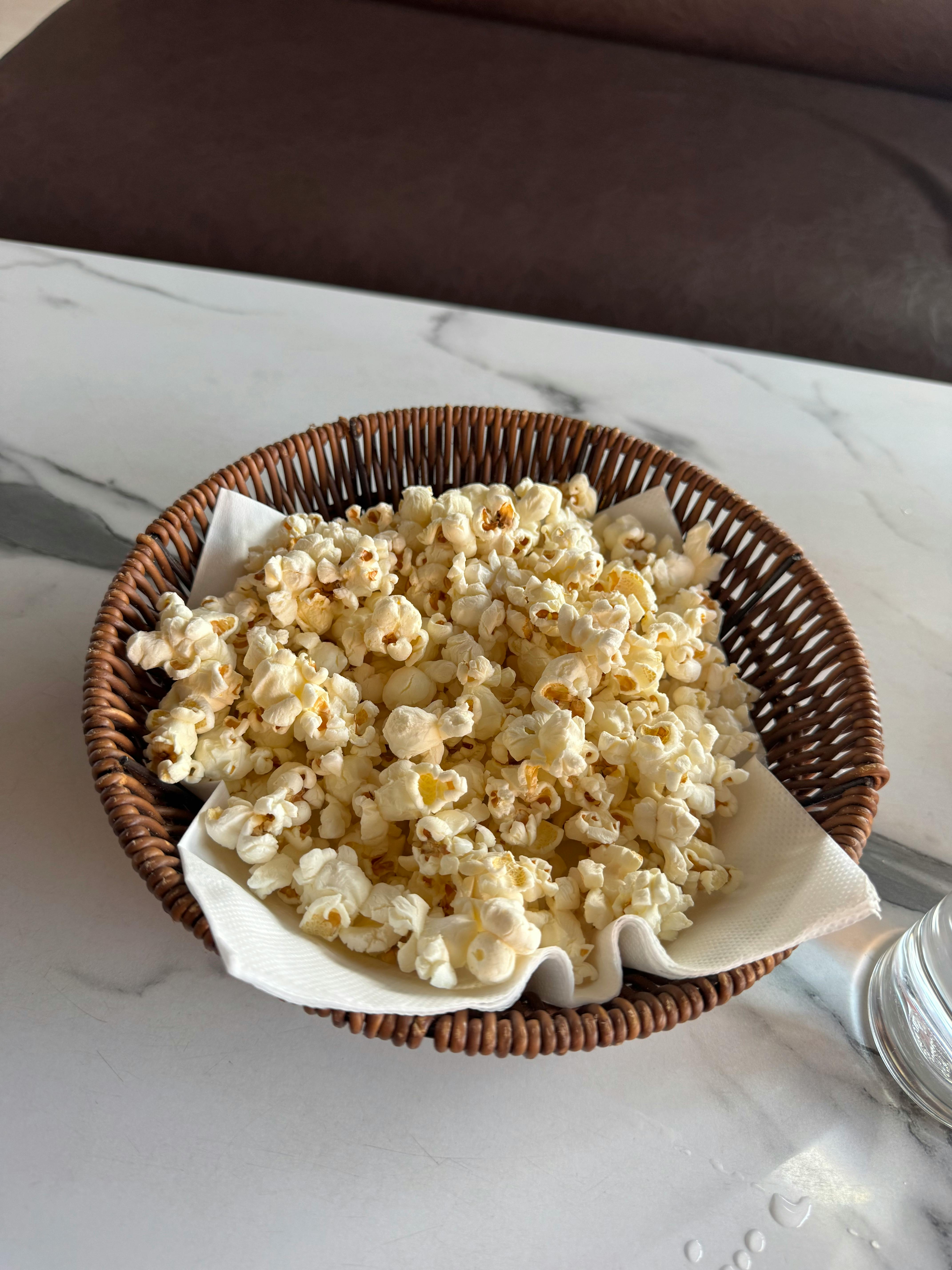 Gratuit Un panier en osier rempli de pop-corn sur une table en marbre à l'intérieur. Photos