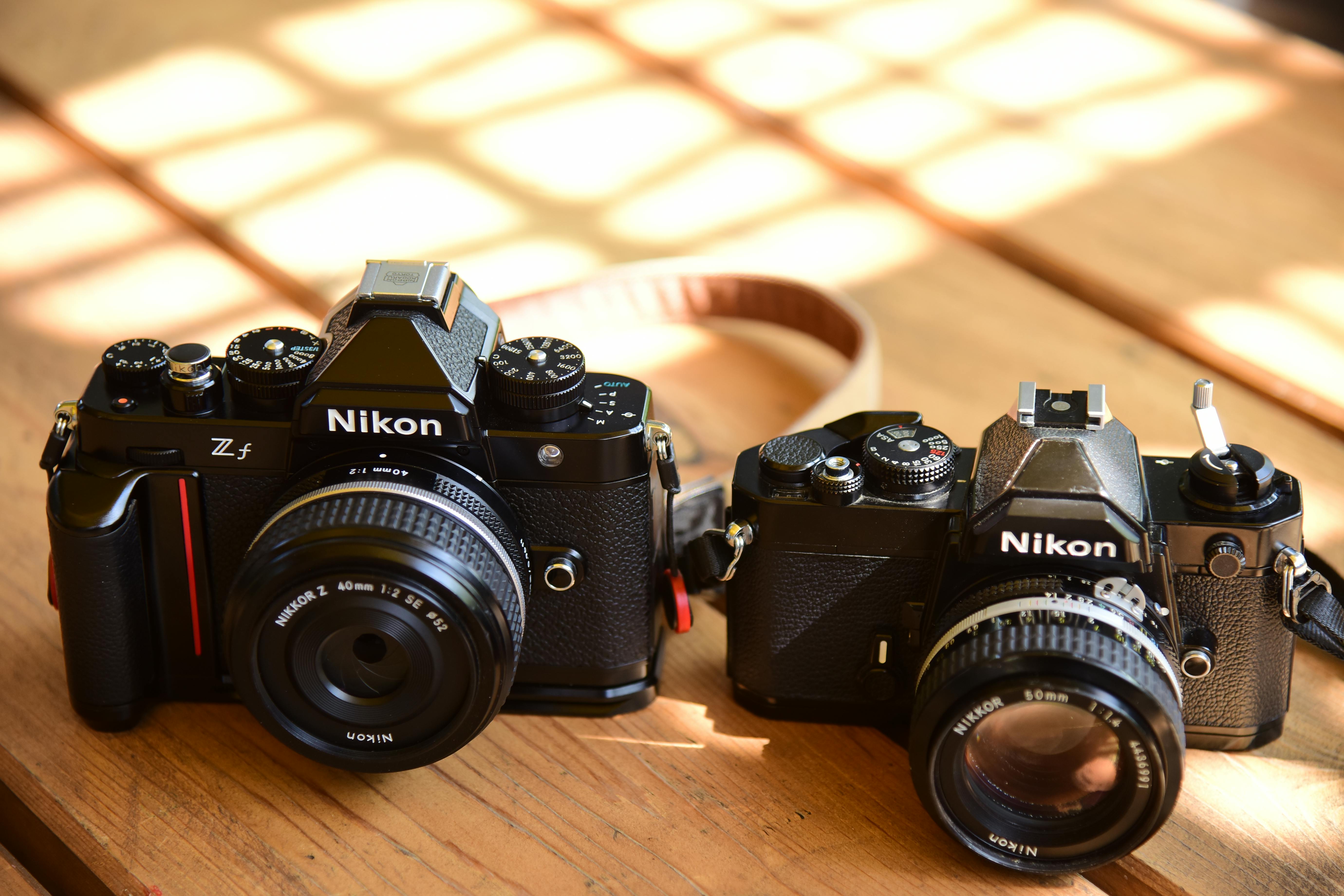 Close-up of vintage and modern Nikon cameras on a wooden table, showcasing design evolution.